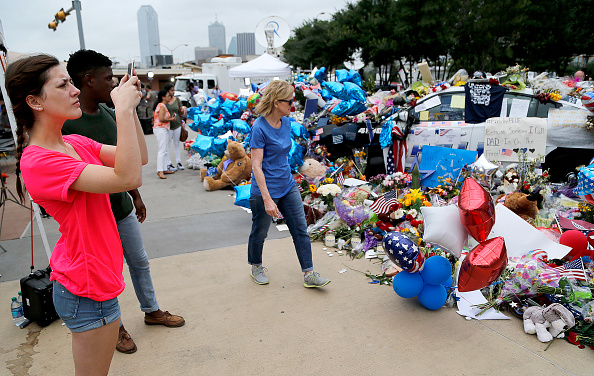 Michaela Granello (L), 19, of Red Oak, takes photo of the growing memorial in front of the Jack Evans Police Headquarters building on July 11, 2016 in Dallas, Texas.