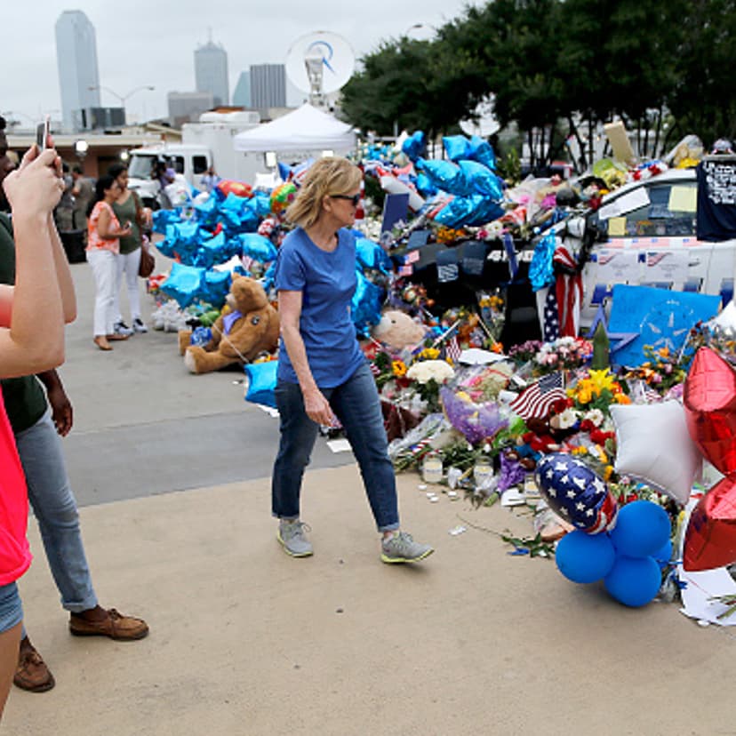 Michaela Granello (L), 19, of Red Oak, takes photo of the growing memorial in front of the Jack Evans Police Headquarters building on July 11, 2016 in Dallas, Texas.