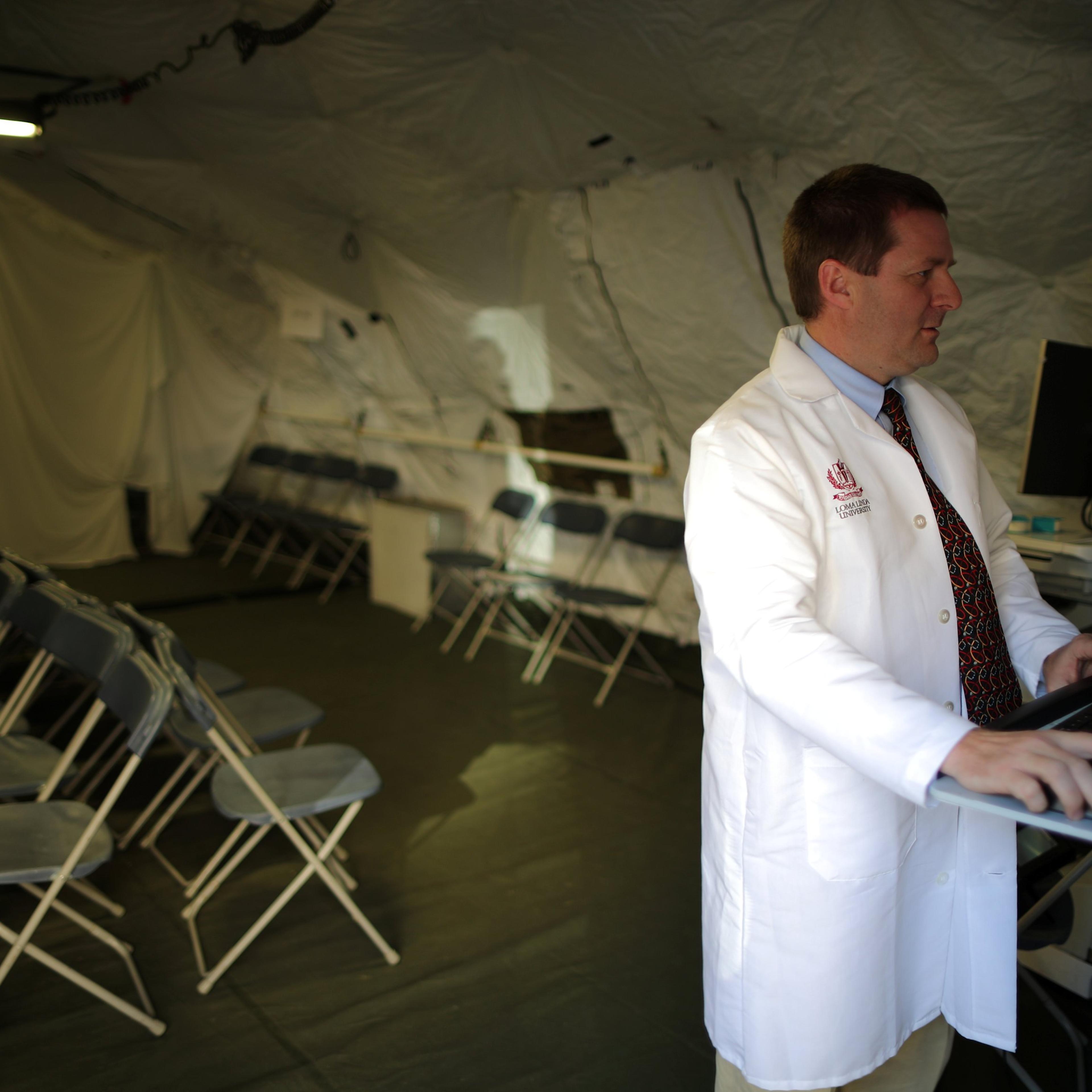 Dr Adrian Cotton stands inside a triage surge tent at Loma Linda University Health Center for patients infected with an influenza A strain known as H3N2, in Loma Linda