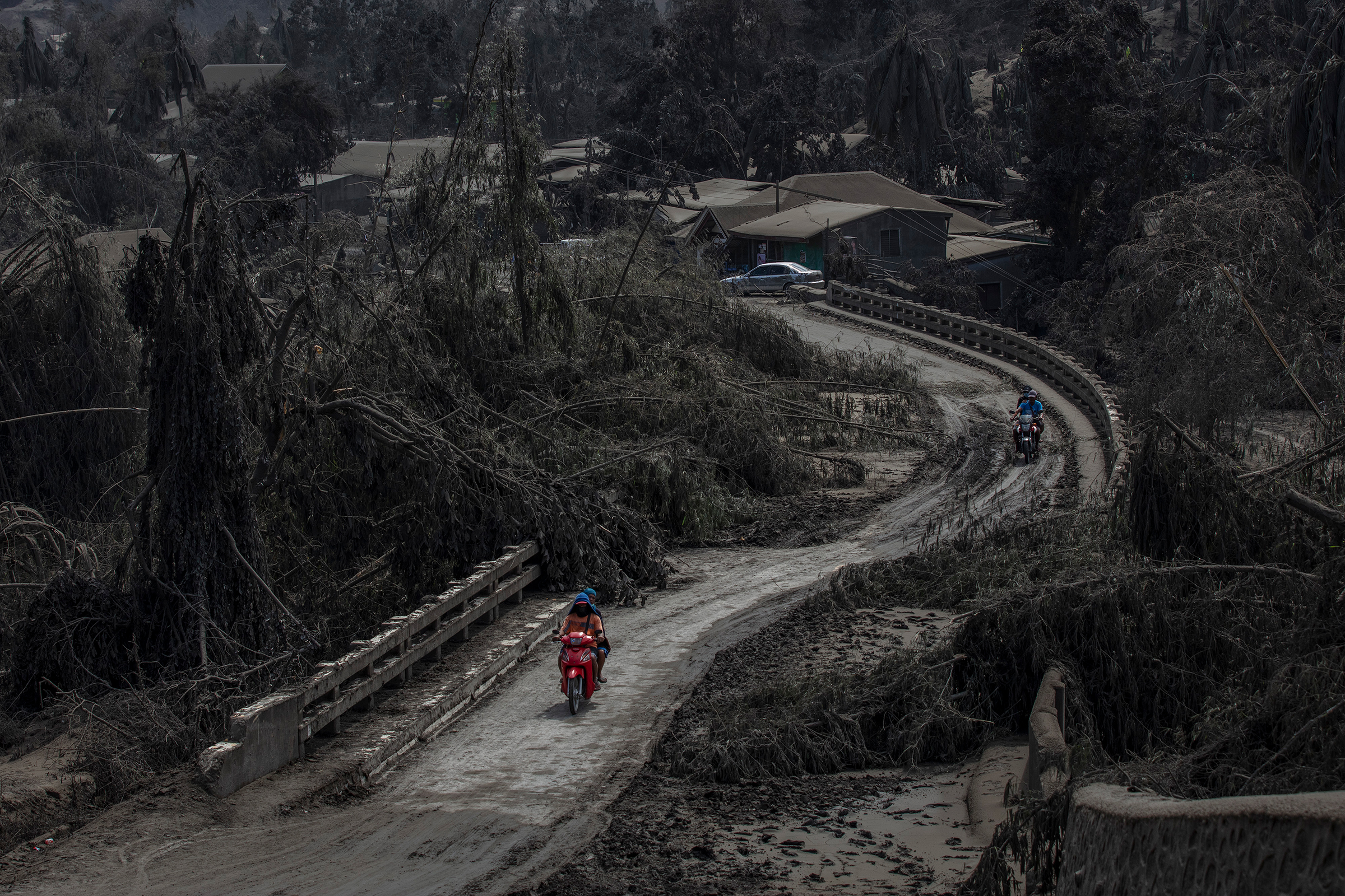 Motorists cross a bridge partially blocked by trees, brought down by volcanic ash from the recent eruption, in Laurel.