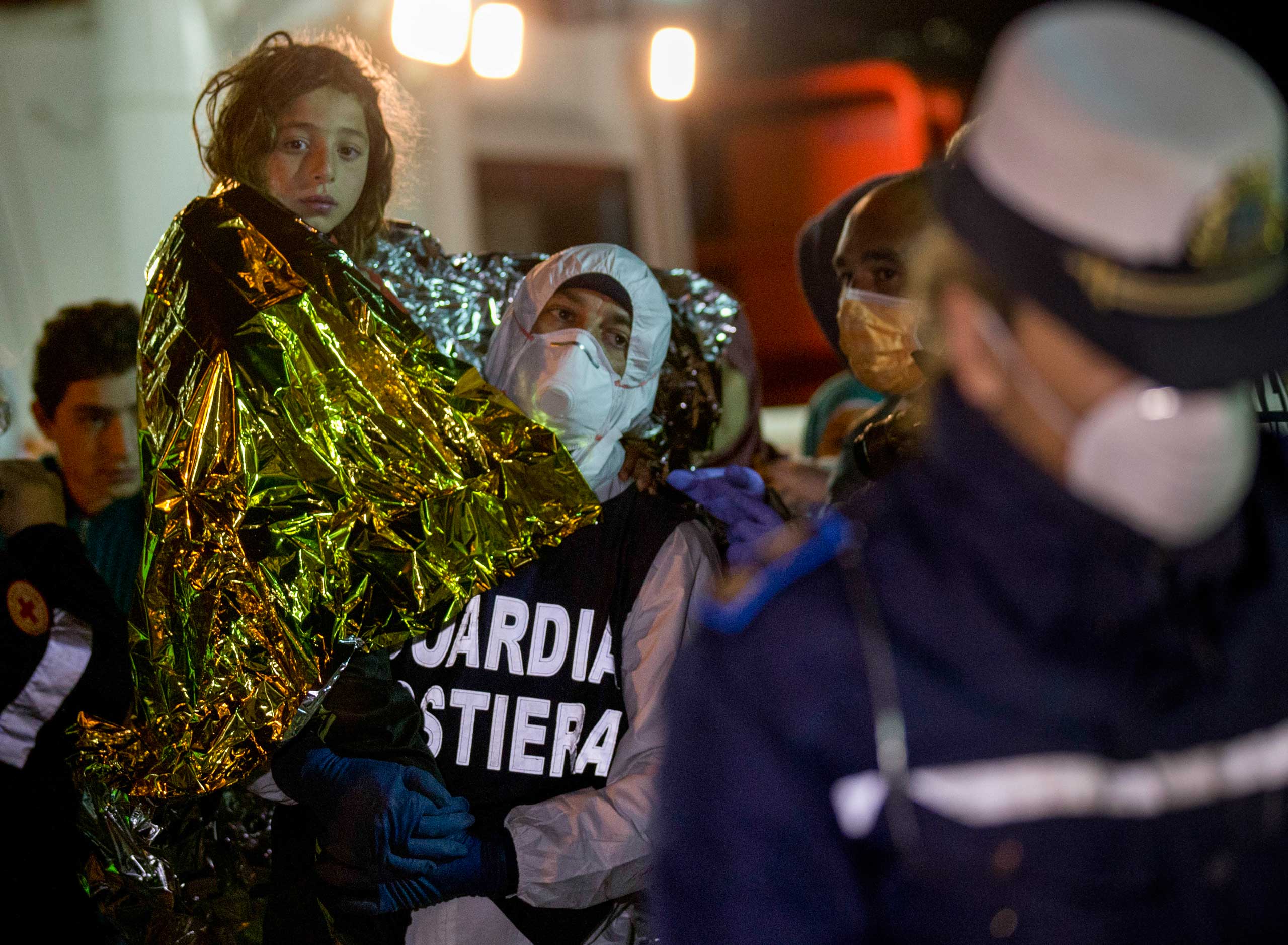 A migrant is helped disembark in the Sicilian harbor of Pozzallo, Italy, early, April 20, 2015.