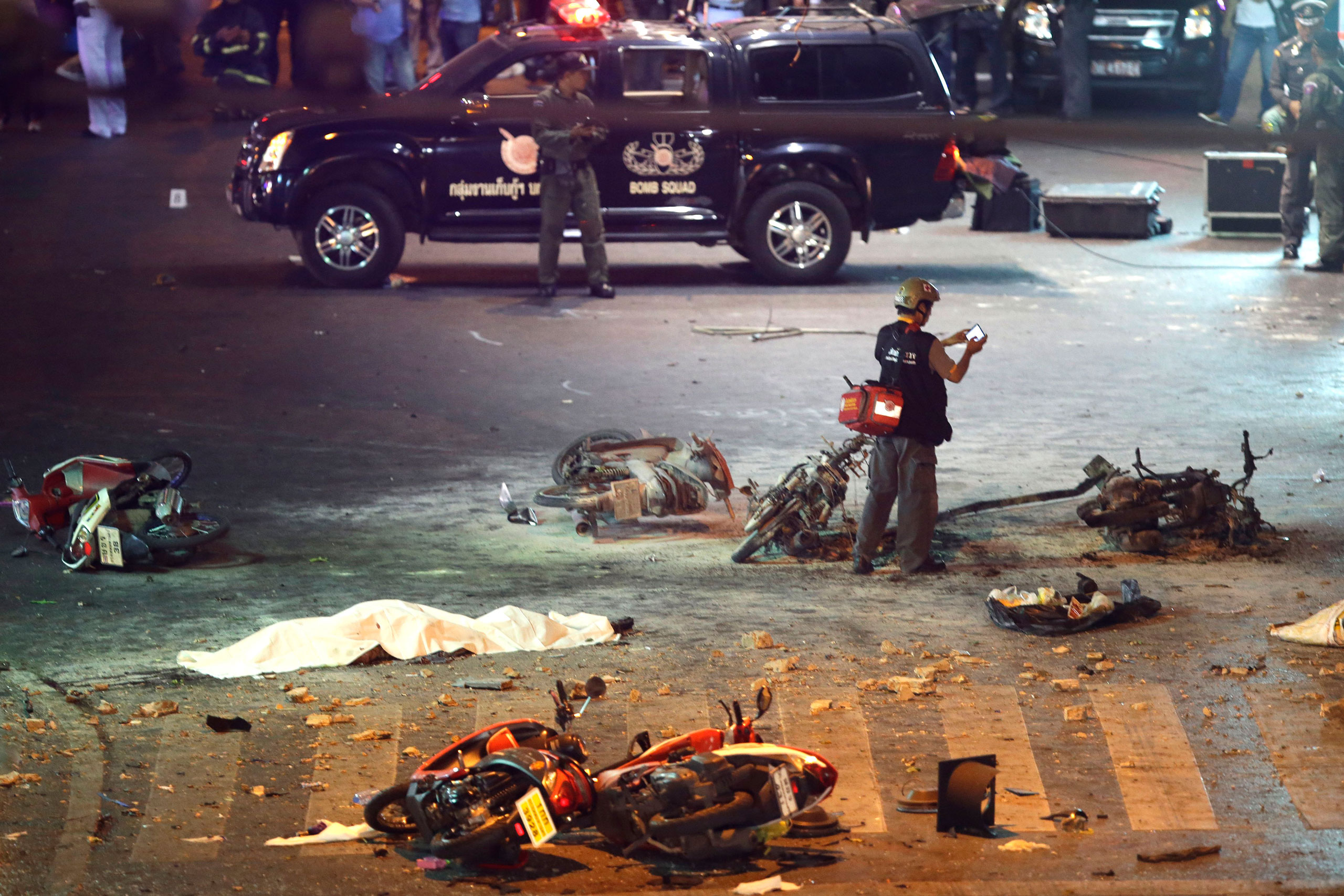 A policeman photographs debris from an explosion in central Bangkok, Thailand, Monday, Aug. 17, 2015. A large explosion rocked a central Bangkok intersection during the evening rush hour, killing at least three people and injuring 25 others, police said.