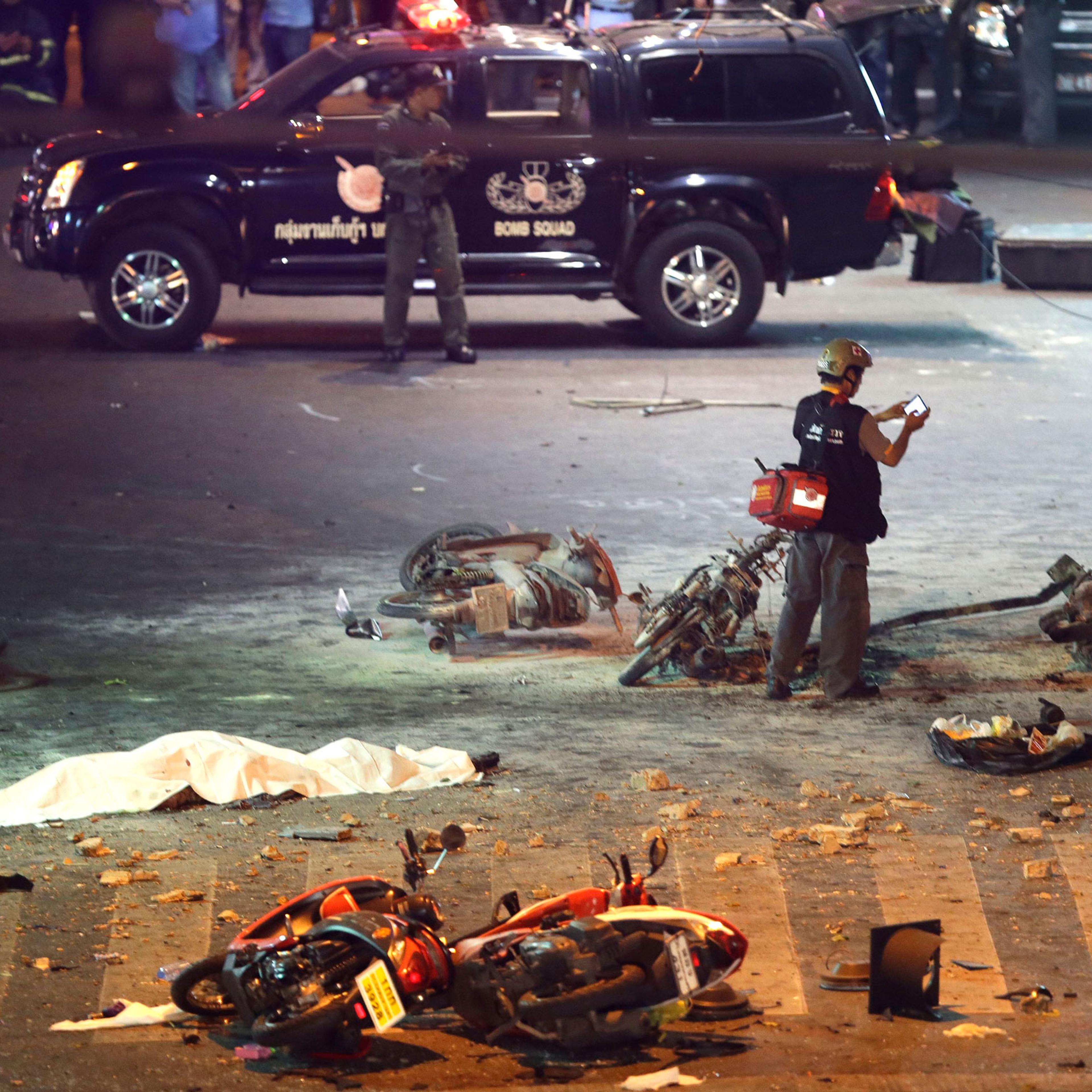 A policeman photographs debris from an explosion in central Bangkok, Thailand, Monday, Aug. 17, 2015. A large explosion rocked a central Bangkok intersection during the evening rush hour, killing at least three people and injuring 25 others, police said.
