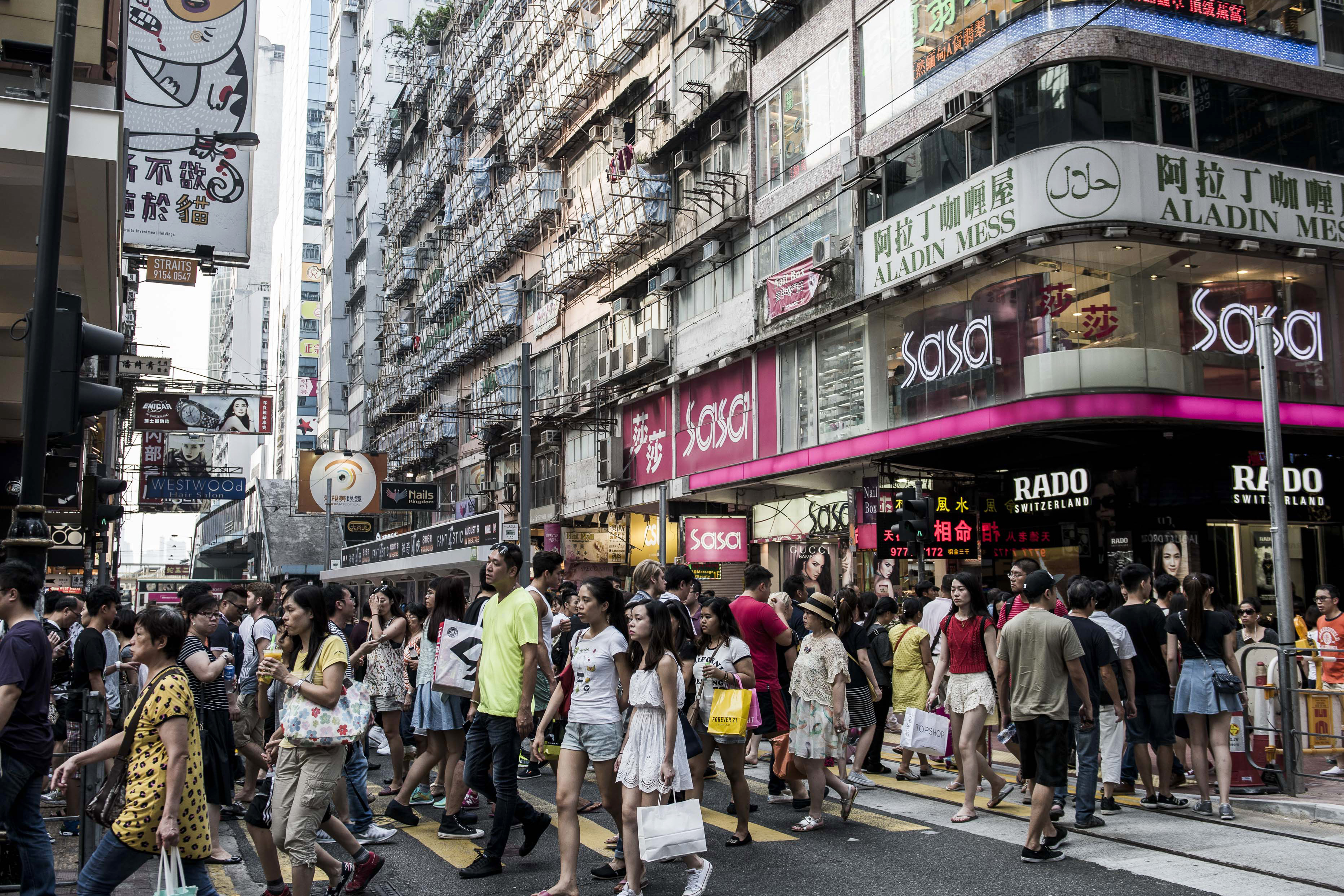Shoppers and pedestrians cross a road on Russell Street in the Causeway Bay shopping district of Hong Kong, China, on Sunday, Aug. 9, 2015. Landlords on Hong Kong's Russell Street a year ago could boast the highest retail rents in the world. Now they are