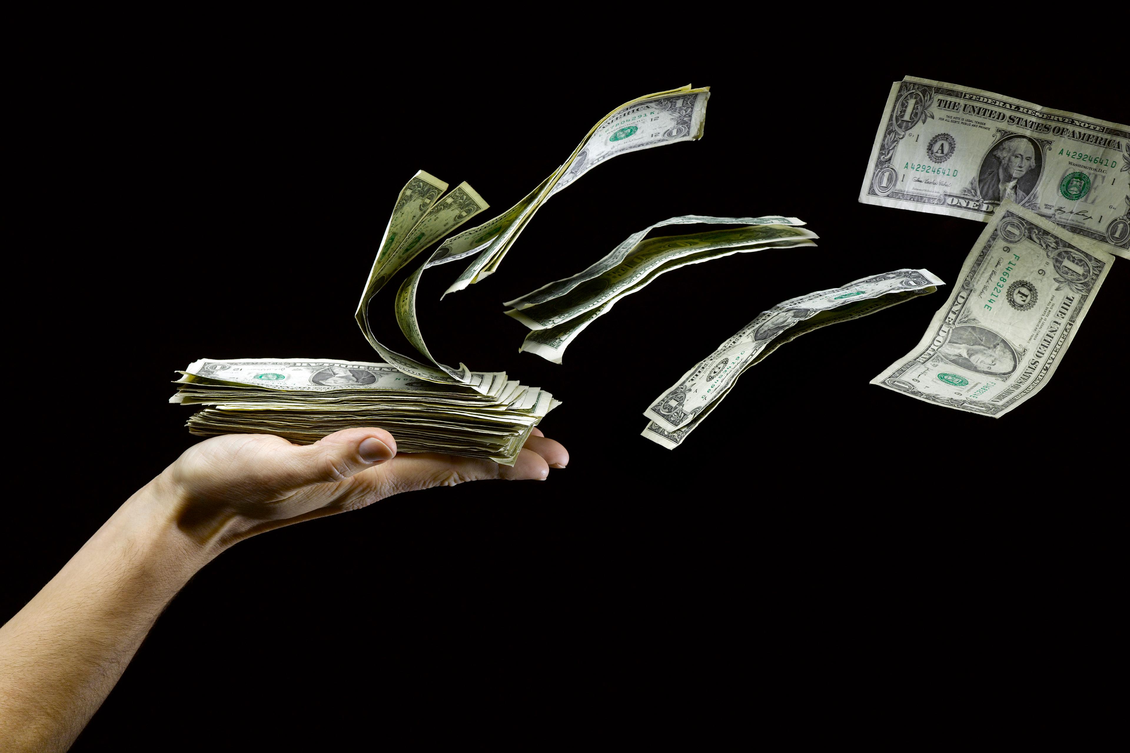 US Paper Money Flying out of Man's Hand