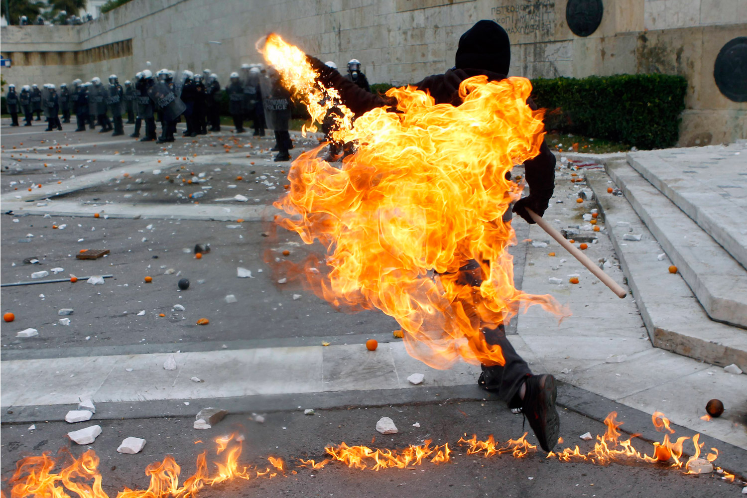 December 6, 2011. A protester hurls a petrol bomb toward riot police in Athens’ Syntagma Square, the center of months of demonstrations in Greece. Activists were marking the anniversary of the 2008 shooting of a student by police. 