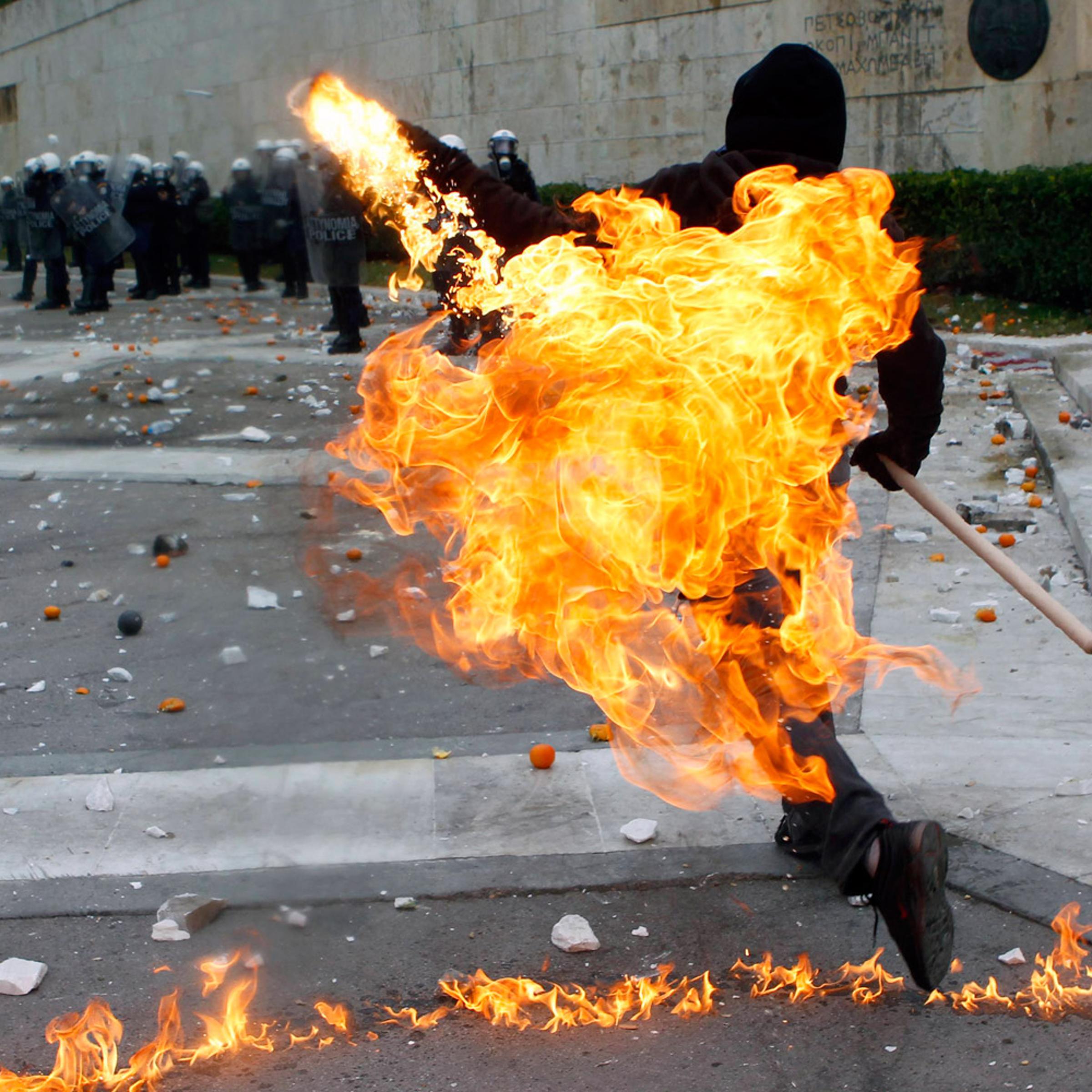 December 6, 2011. A protester hurls a petrol bomb toward riot police in Athens’ Syntagma Square, the center of months of demonstrations in Greece. Activists were marking the anniversary of the 2008 shooting of a student by police.