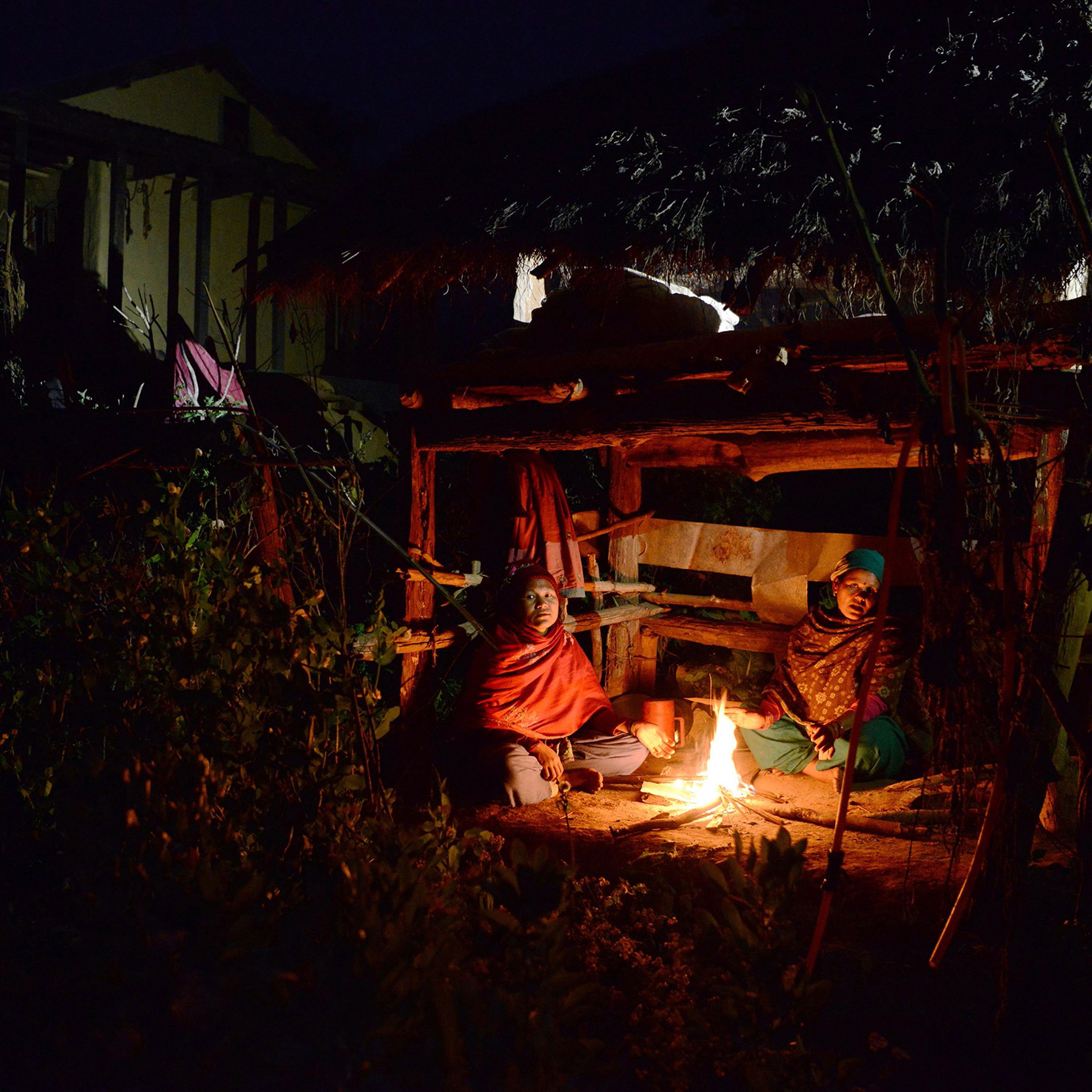 Nepalese women Pabitra Giri (L) and Yum Kumari Giri (R) sit by a fire as they live in a Chhaupadi hut during their menstruation period in Surkhet District, some 520km west of Kathmandu on Feb. 3, 2017.