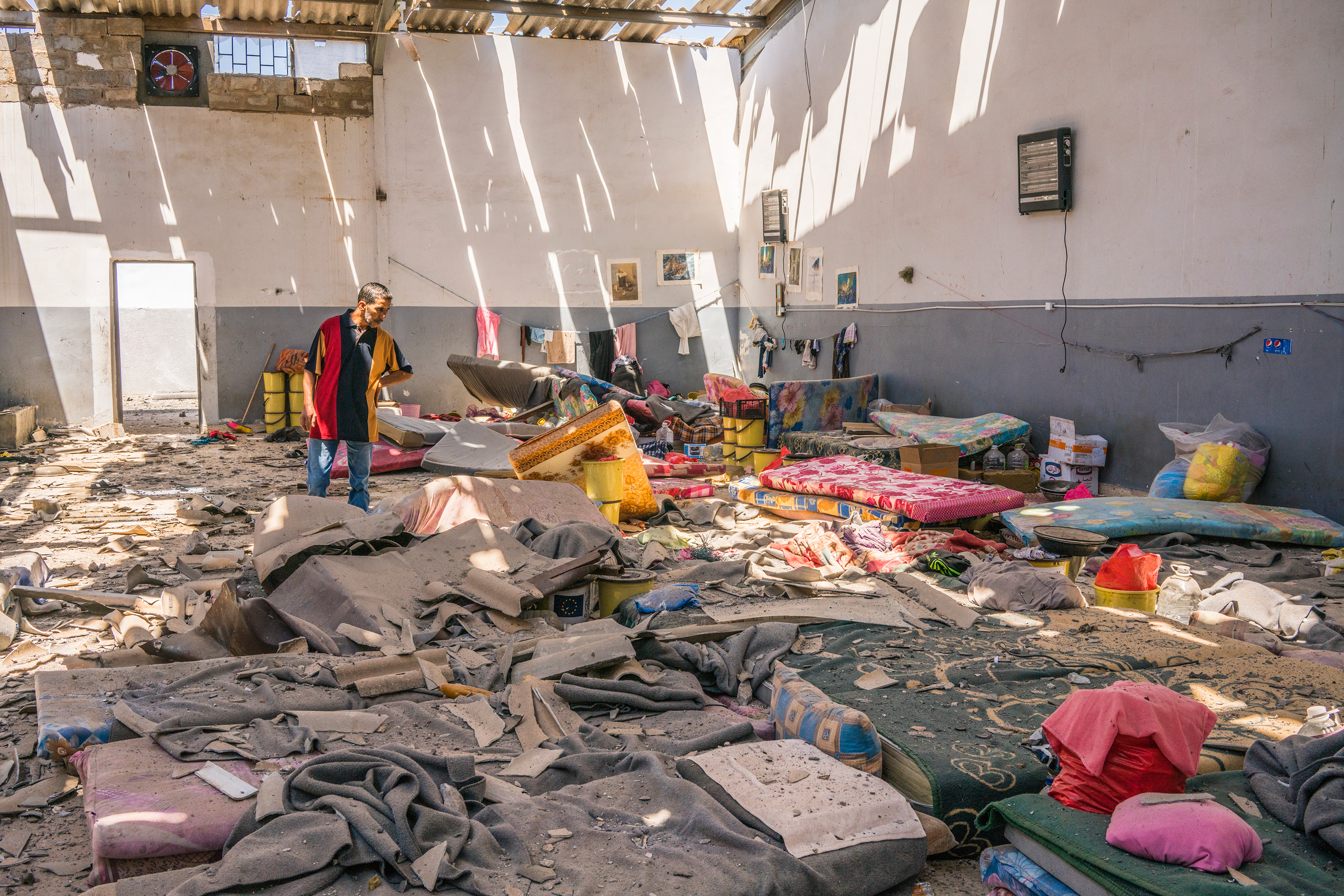 A man inspects damage to an area where migrants slept inside the Tajoura detention center near Tripoli, Libya, on July 3. Dozens of migrants were killed in an attack that was condemned around the world.