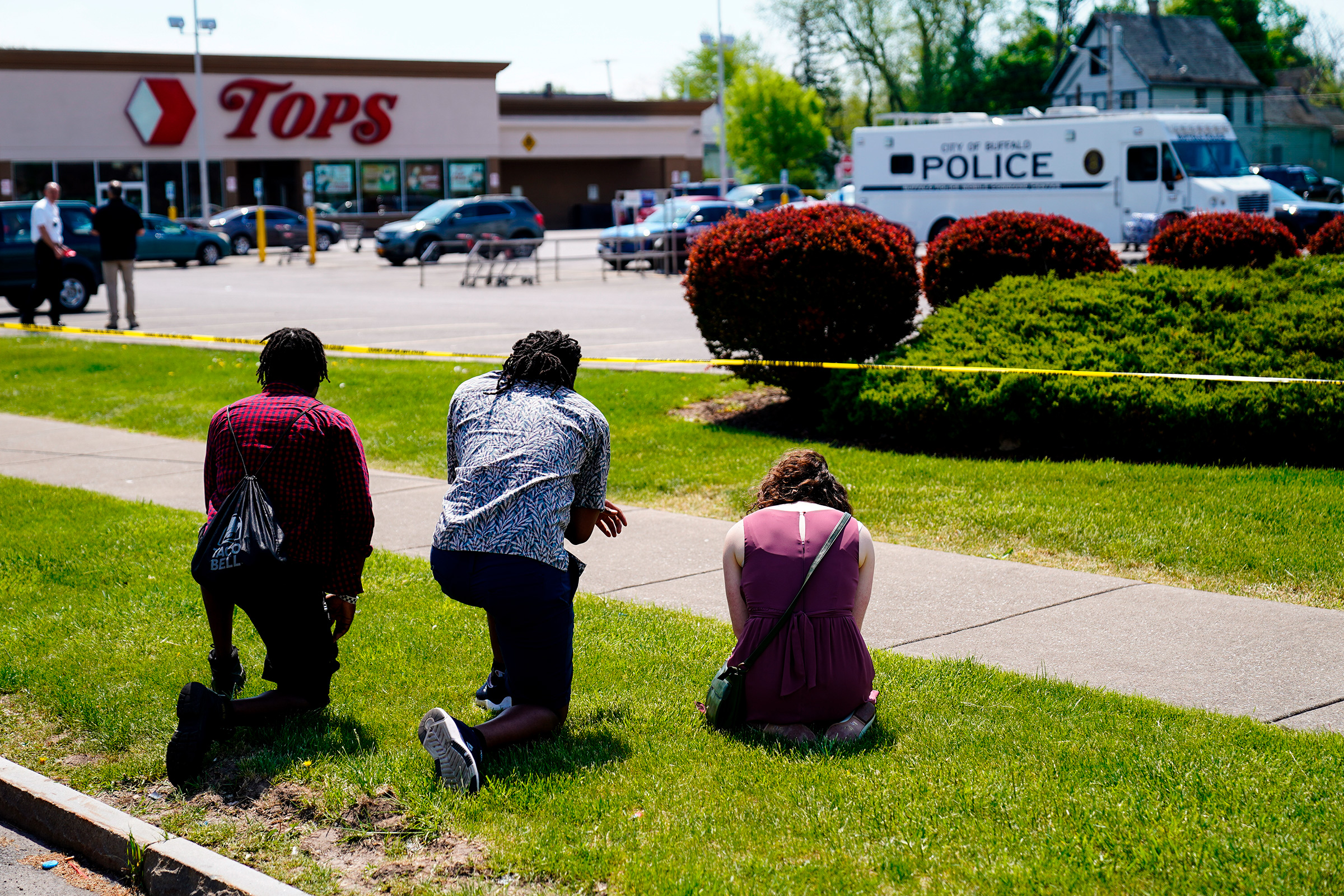 People pray outside the scene of a shooting at Tops supermarket in Buffalo, N.Y., May 15, 2022.