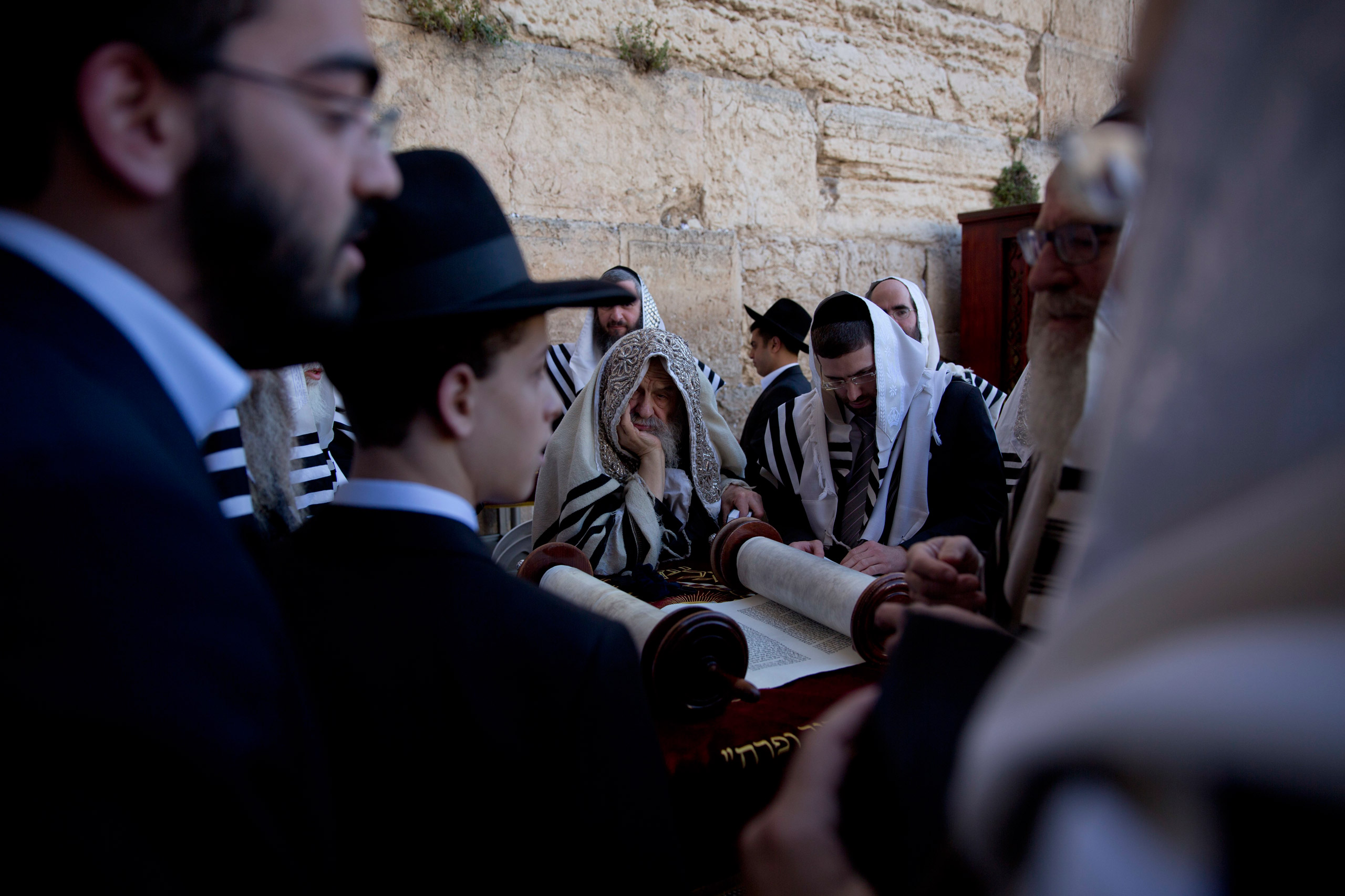 Covered in prayer shawls, ultra-Orthodox Jewish men read from a Thora scroll during the Jewish holiday of Passover in front of the Western Wall, the holiest site where Jews can pray, in Jerusalem's Old City, Sunday, April 24, 2016. (AP Photo/Ariel Schali
