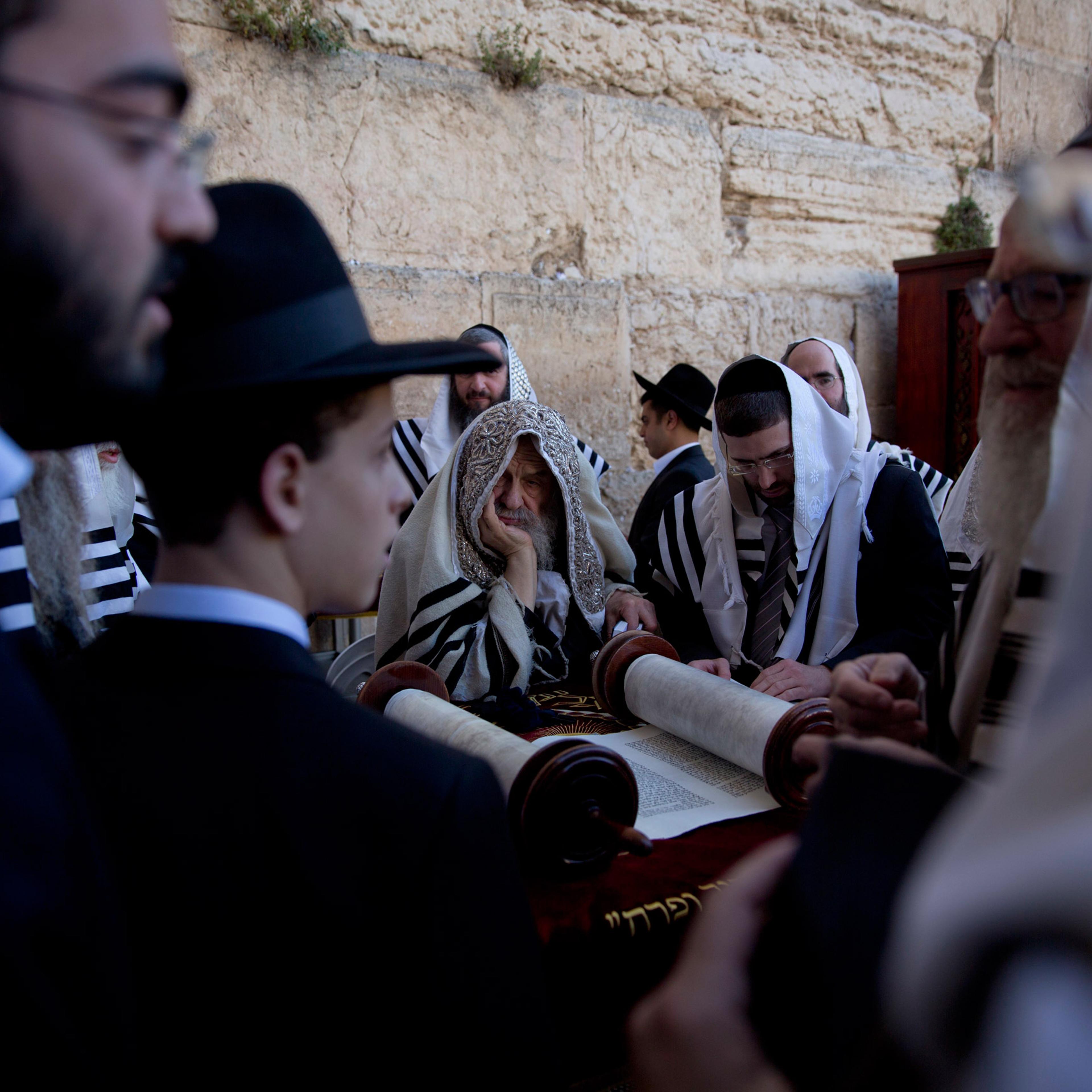 Covered in prayer shawls, ultra-Orthodox Jewish men read from a Thora scroll during the Jewish holiday of Passover in front of the Western Wall, the holiest site where Jews can pray, in Jerusalem's Old City, Sunday, April 24, 2016. (AP Photo/Ariel Schali