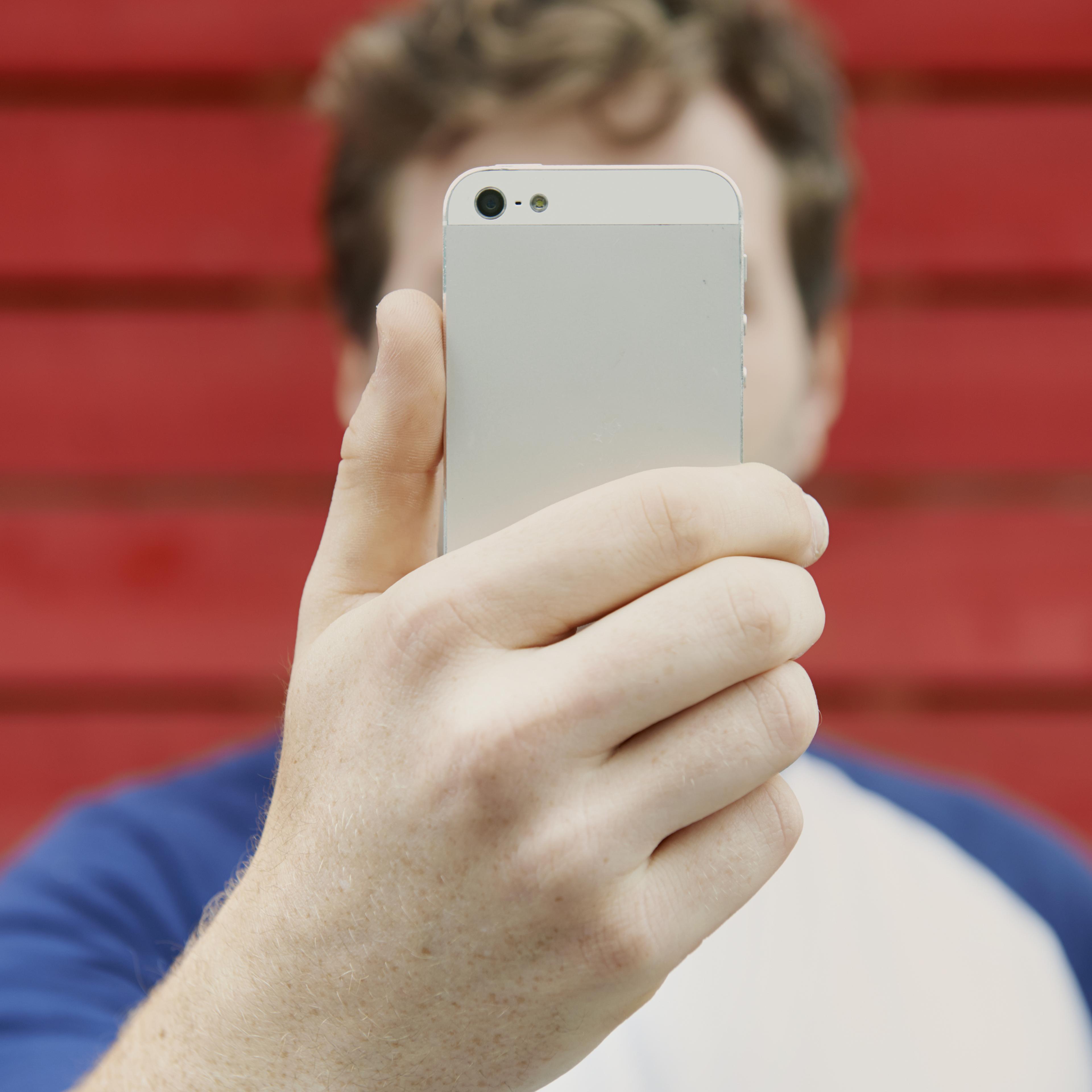 man holding up mobile to take selfie