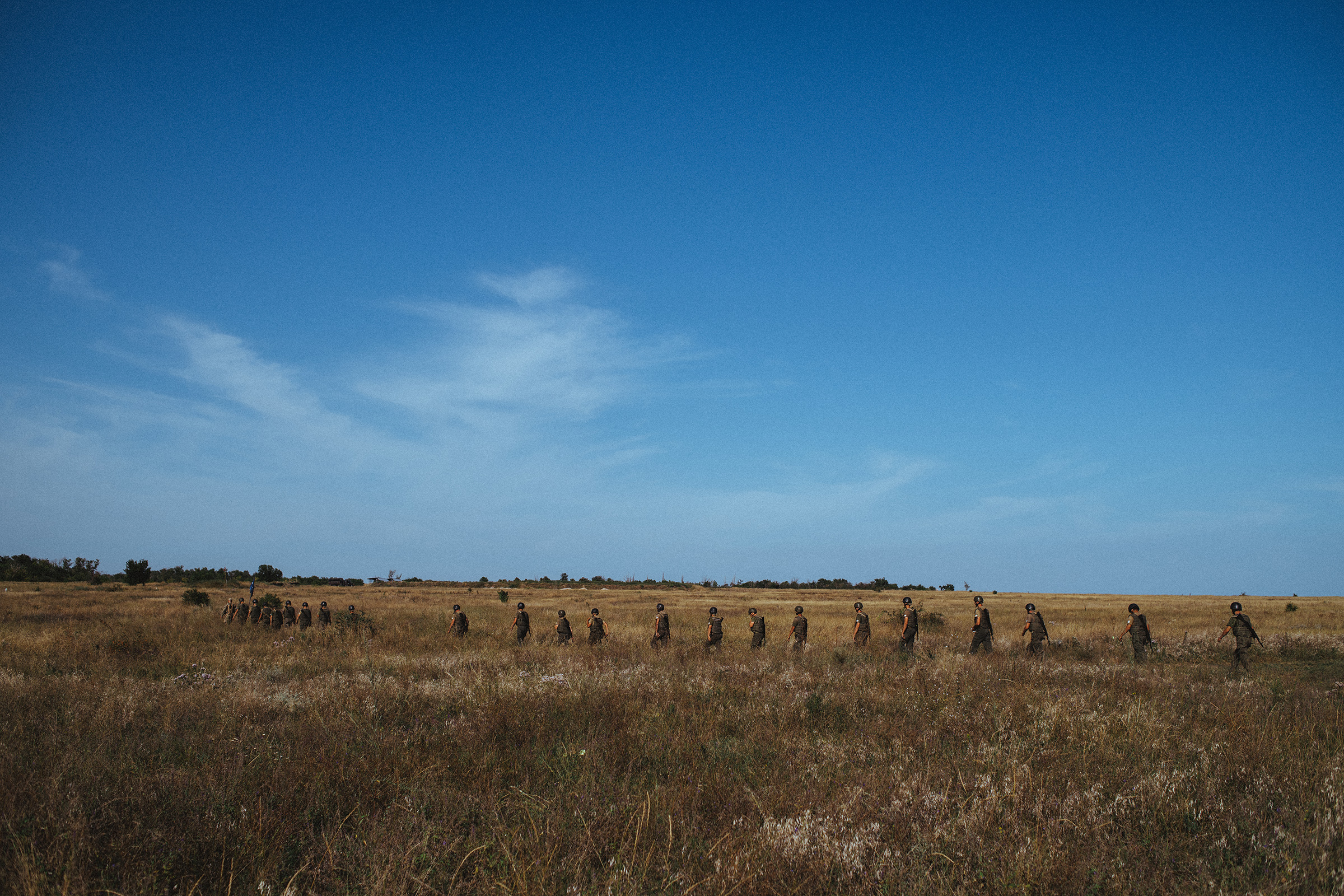 A line of new recruits walk through a field during basic training at the Azov base near Mariupol. Located near the Sea of Azov, from which the movement derives its name, the base is large enough to accommodate drills with Azov's arsenal of artillery piec