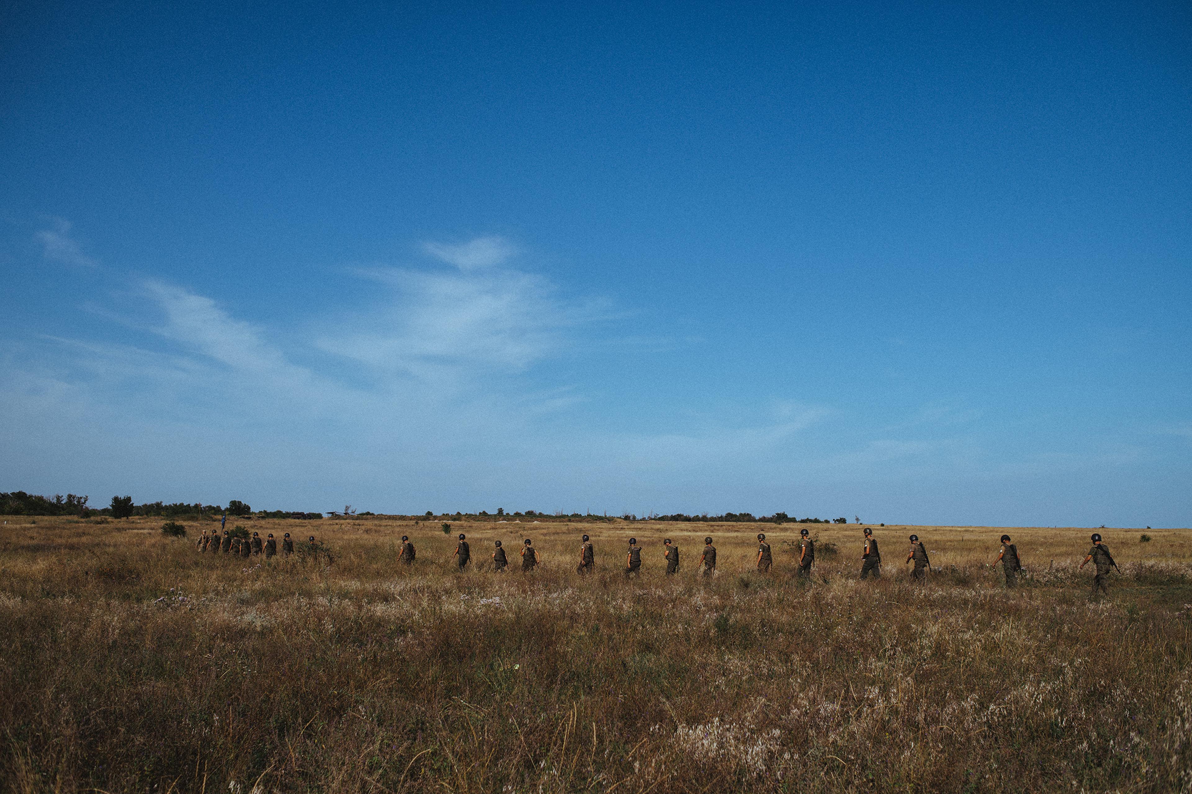 A line of new recruits walk through a field during basic training at the Azov base near Mariupol. Located near the Sea of Azov, from which the movement derives its name, the base is large enough to accommodate drills with Azov's arsenal of artillery piec