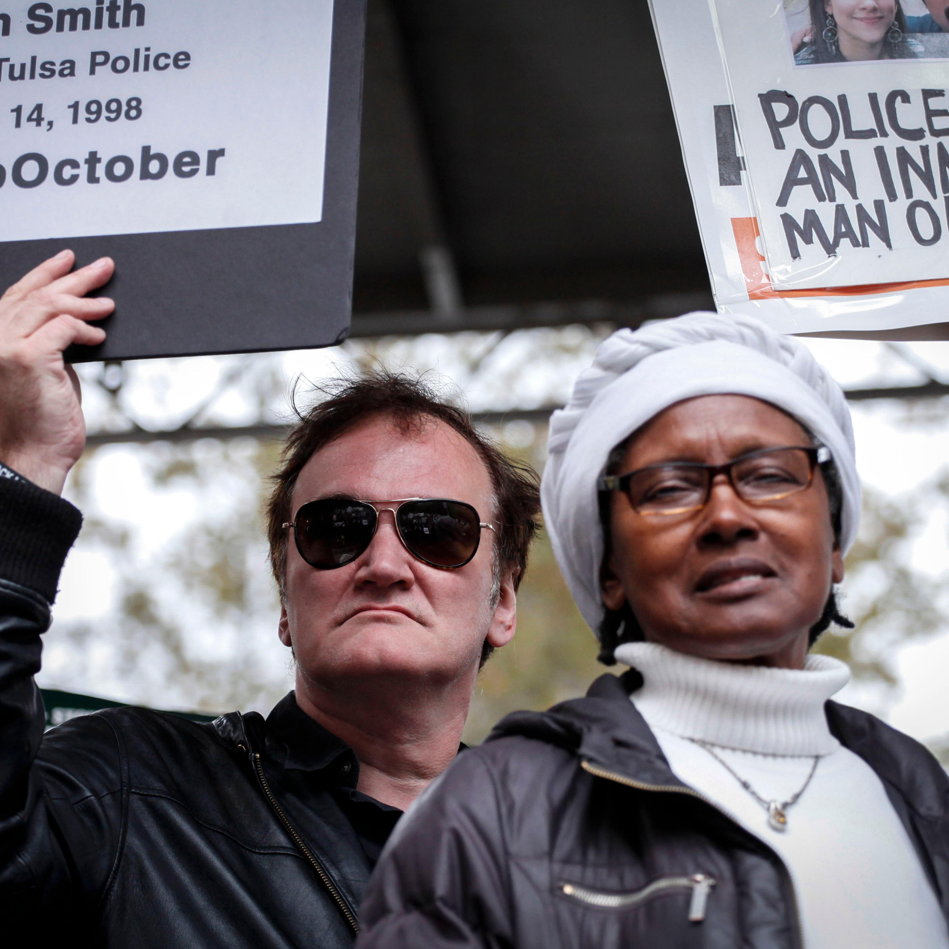 Director Quentin Tarantino holds a banner as attends a rally to denounce police brutality in New York City on Oct.r 24, 2015.