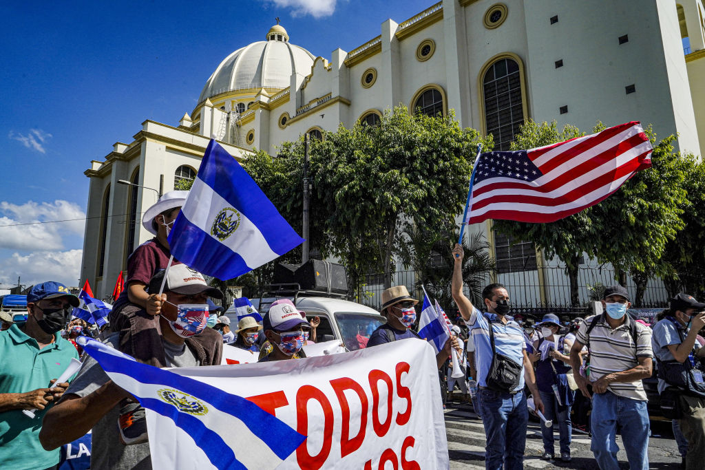 Protesters wave the flags of the U.S. and El Salvador