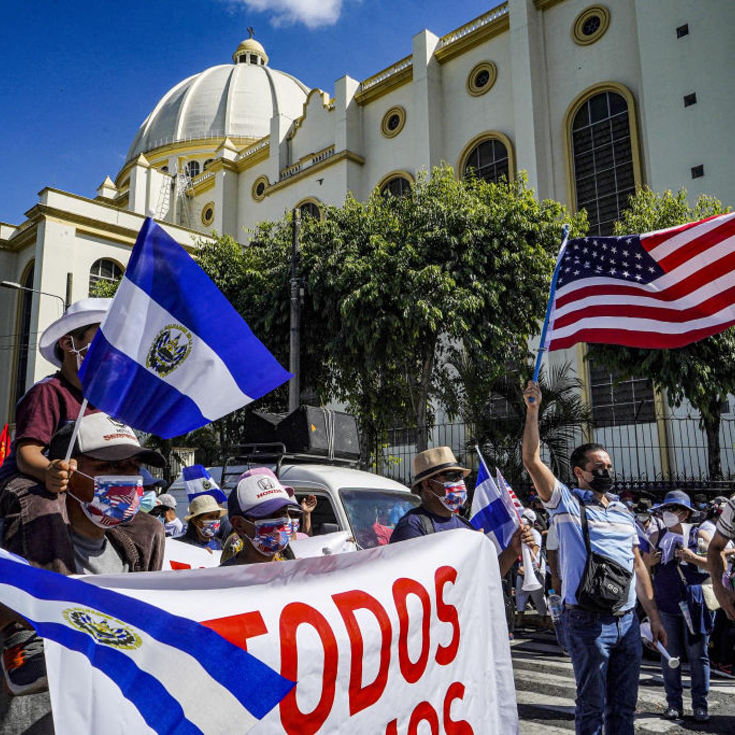 Protesters wave the flags of the U.S. and El Salvador