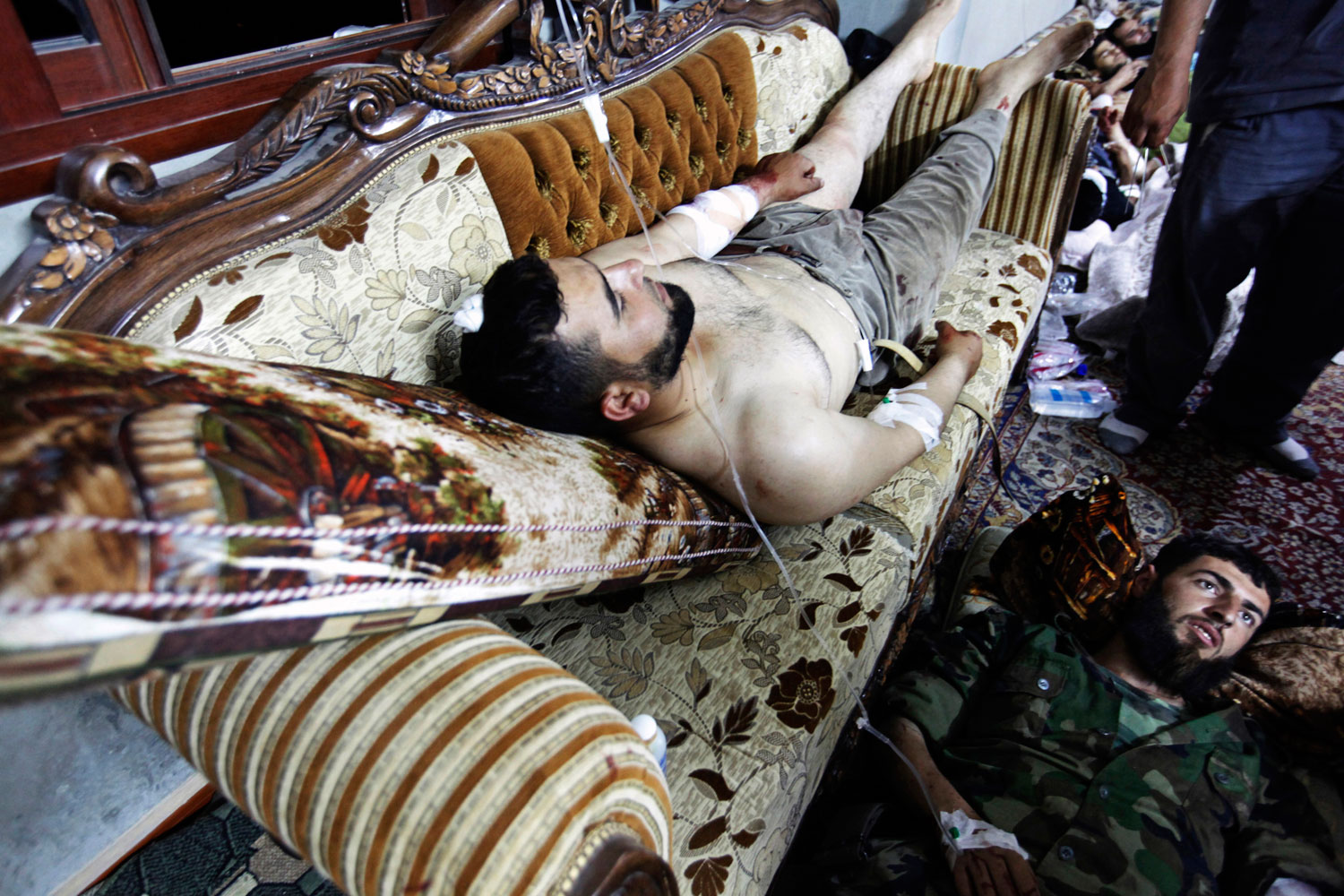 Medical volunteers treat wounded Free Syrian Army soldiers inside a home after the field hospital reached capacity