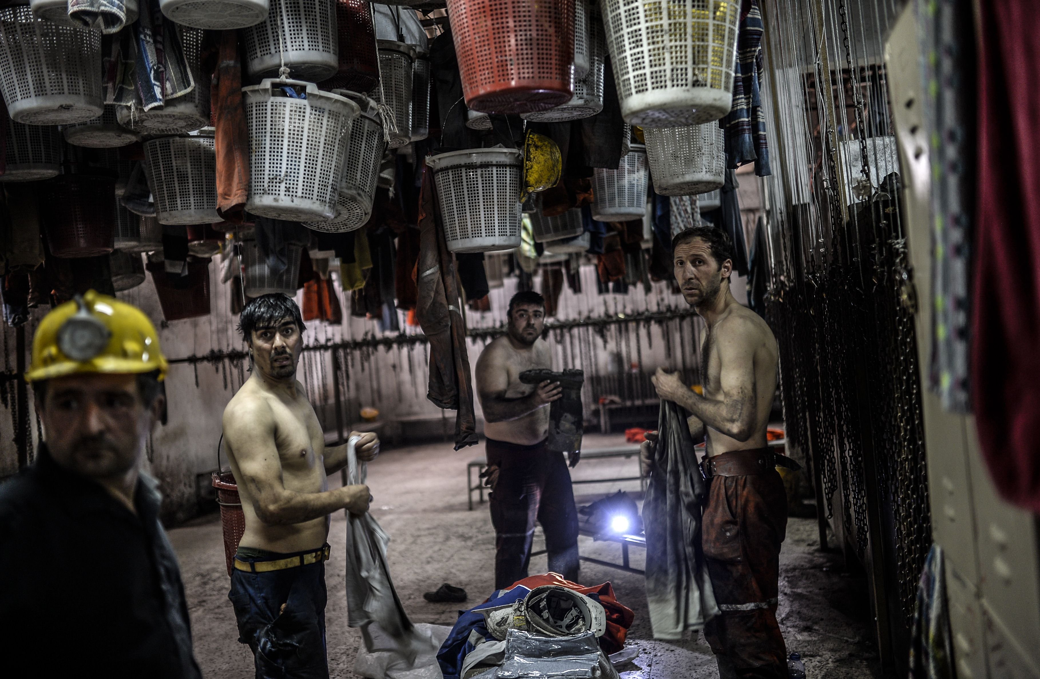 Miners change their clothes in an outside building after searching for hours hundreds of their co-workers who remain trapped underground on May 14, 2014 after an explosion and fire in their coal mine in the western Turkish province of Manisa.