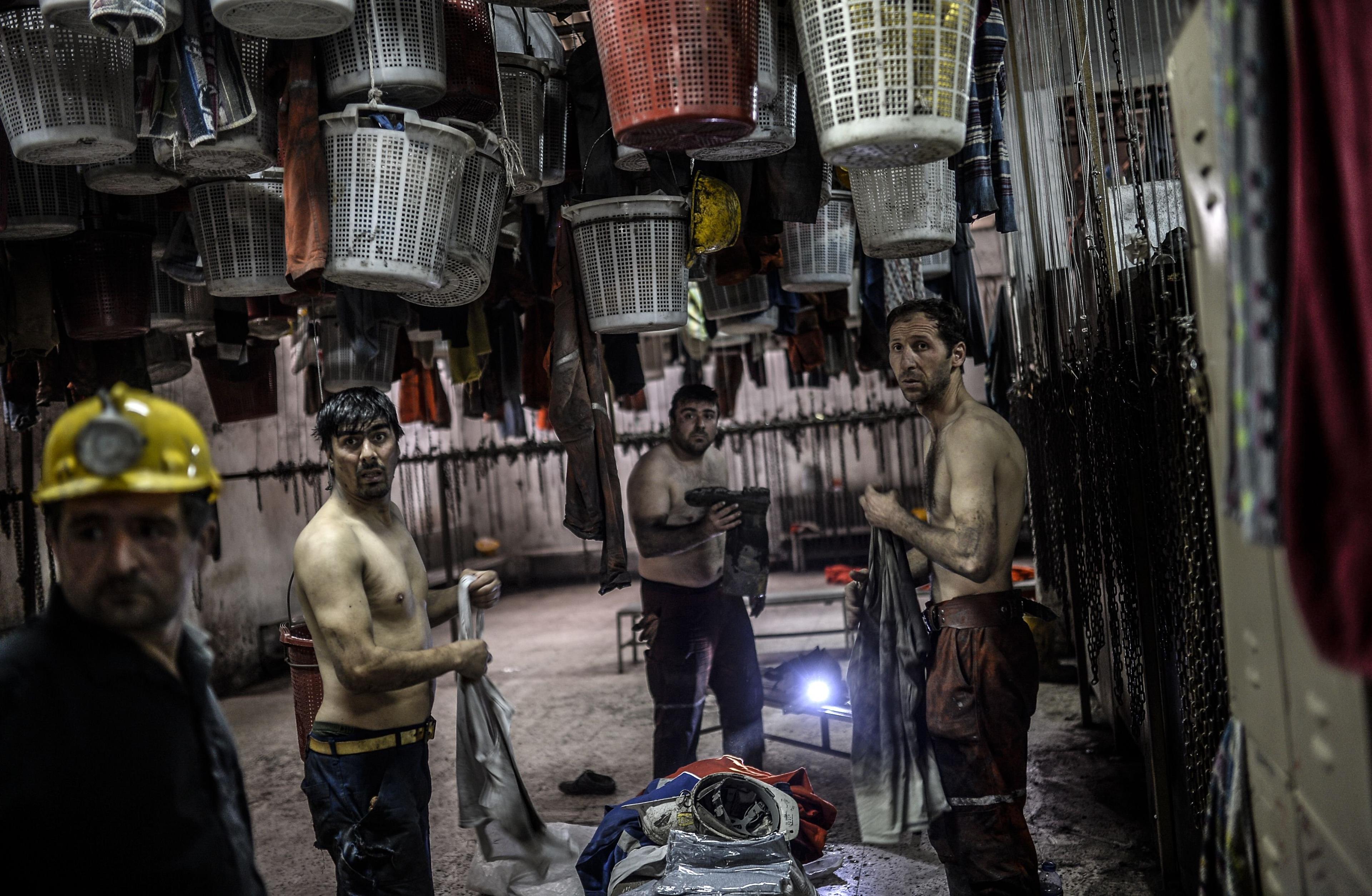 Miners change their clothes in an outside building after searching for hours hundreds of their co-workers who remain trapped underground on May 14, 2014 after an explosion and fire in their coal mine in the western Turkish province of Manisa.