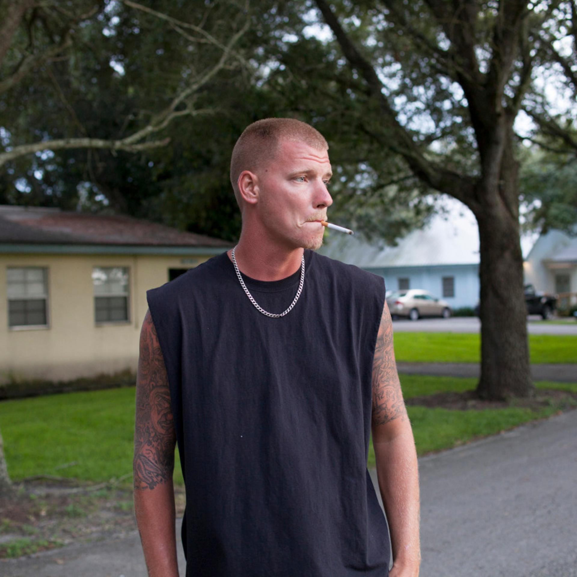 David smoking a cigarette outside his house.