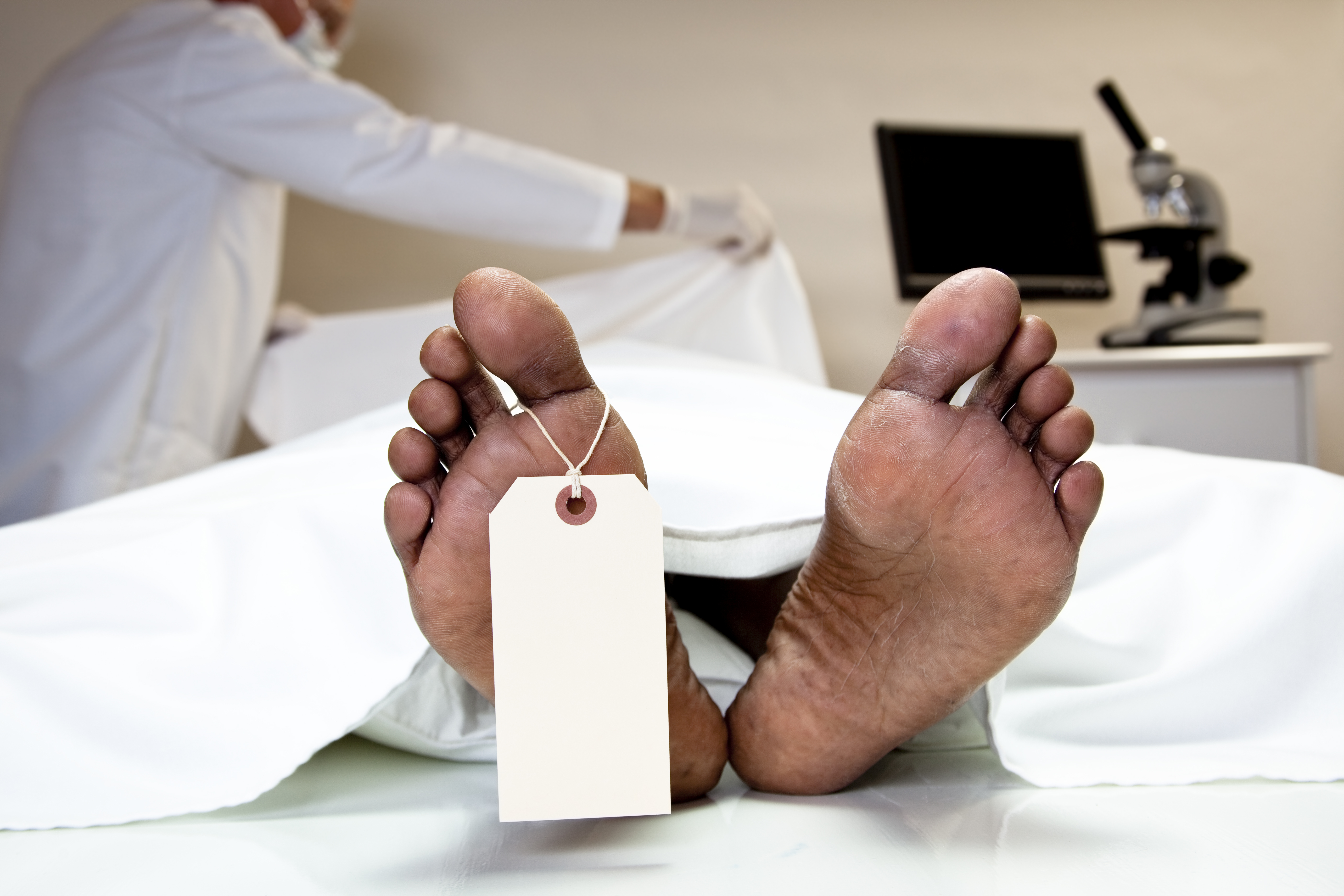 Mortician covering dead body in morgue