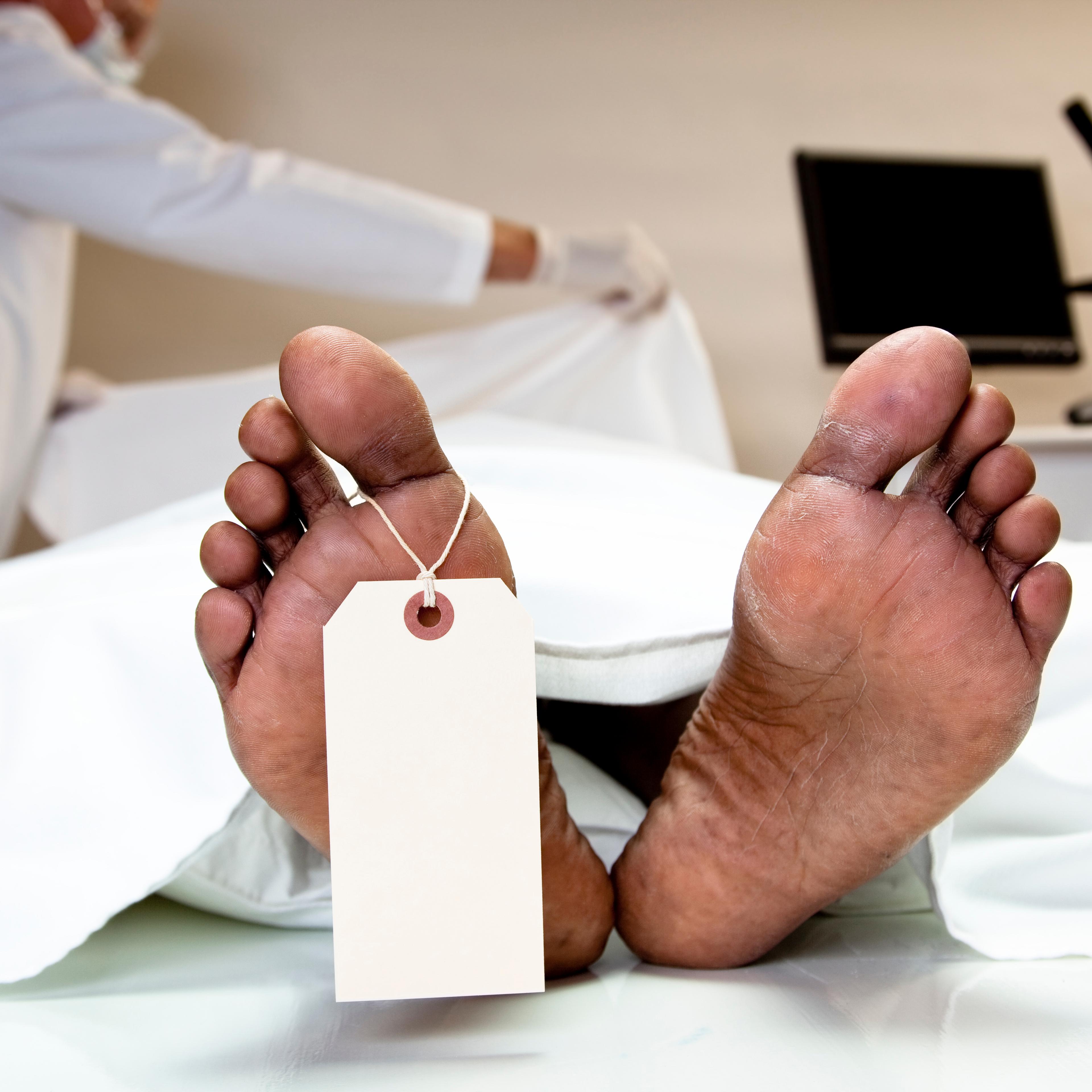 Mortician covering dead body in morgue