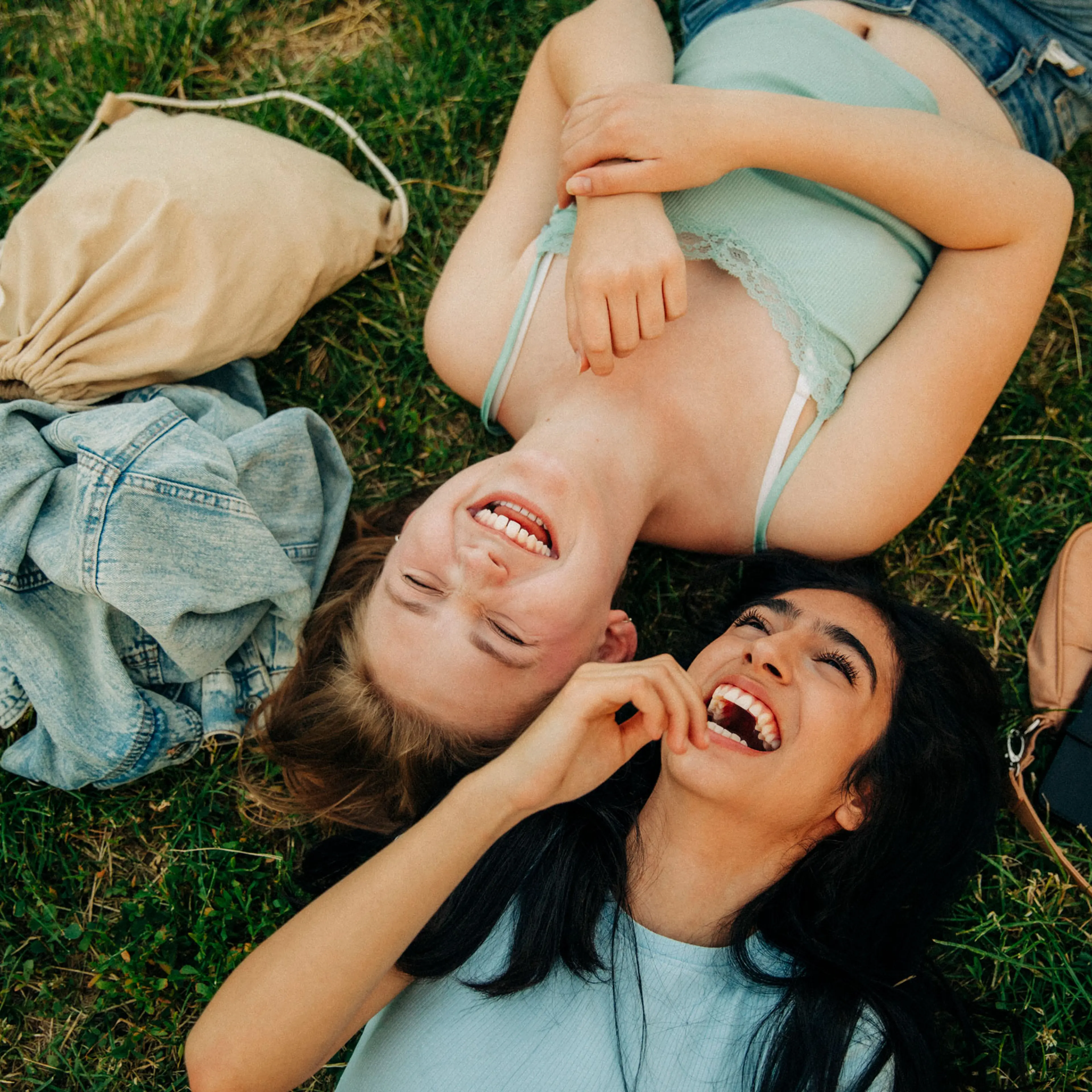 Cheerful teenage girls lying together at park
