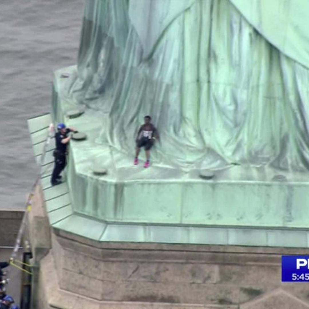 In this image made from video by PIX11, Patricia Okoumou leans against the robes of the Statue of Liberty on Liberty Island, in New York, July 4, 2018.