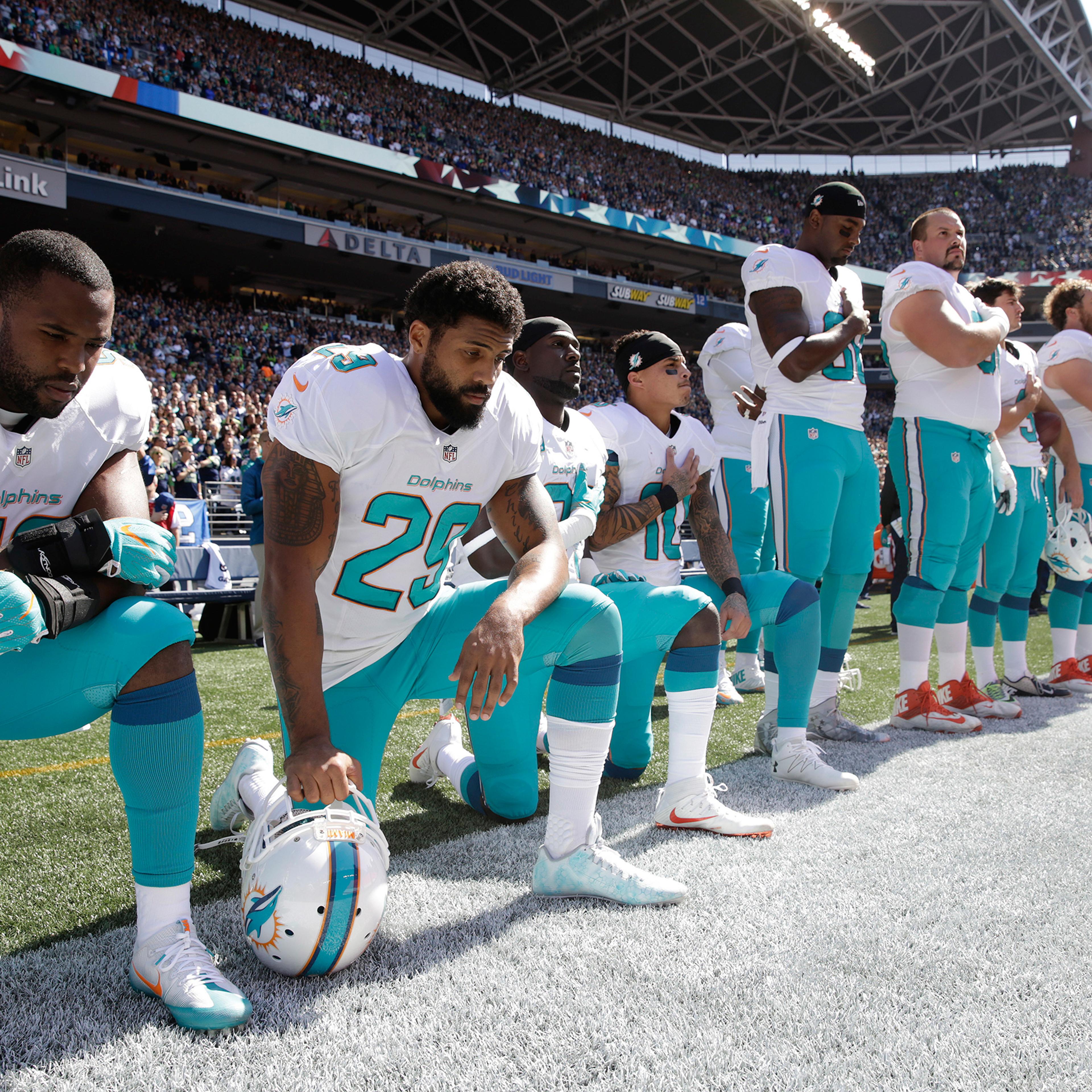 Jelani Jenkins, Arian Foster, Michael Thomas, and Kenny Stills of the Miami Dolphins kneel during the singing of the national anthem before a game against the Seattle Seahawks in Seattle on Sept. 11, 2016.