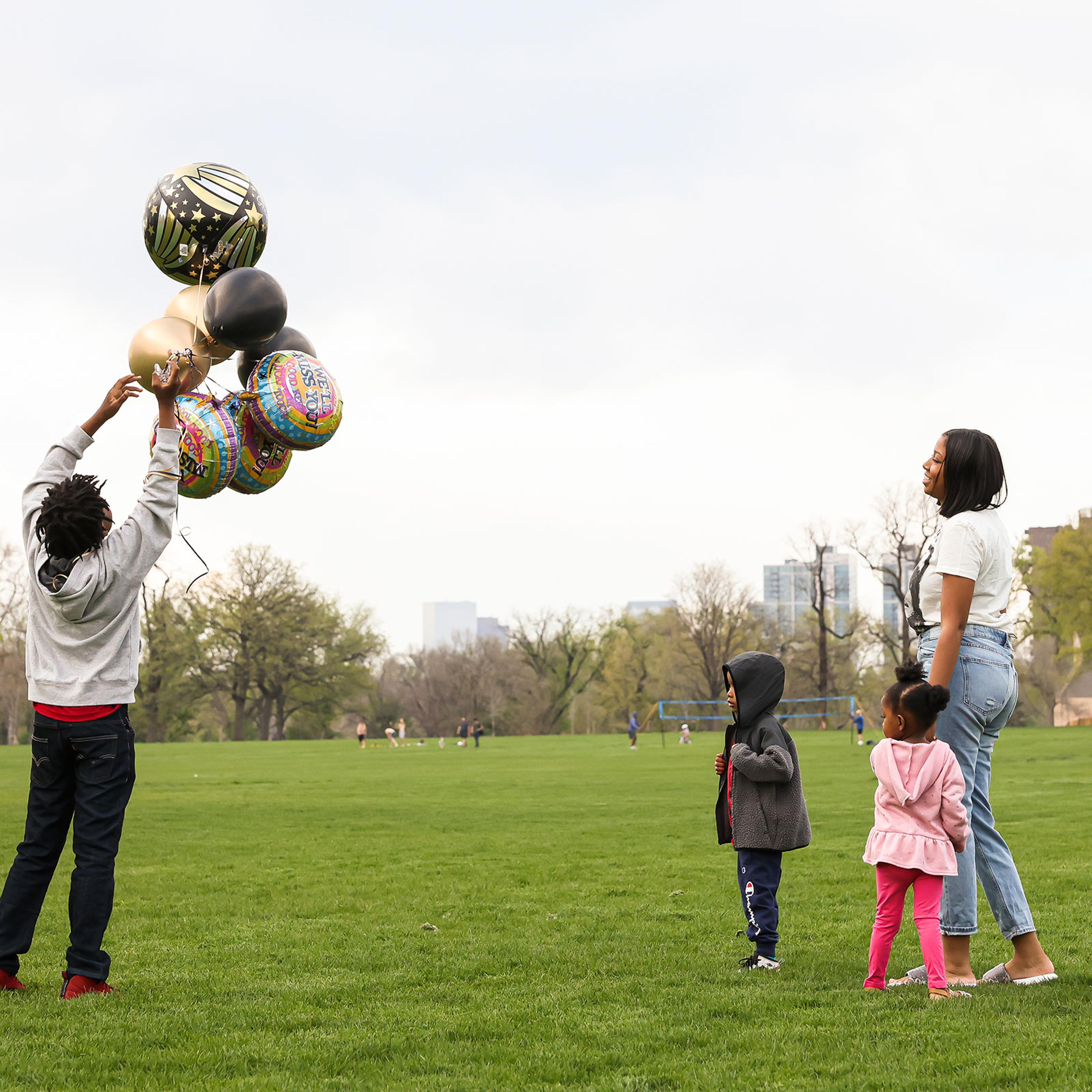 Nehemiah prepares to release balloons in commemoration of the death of his father while his mother Ashley, his 4-year-old bother, Prince, and 3-year-old sister, Zyla, watch nearby