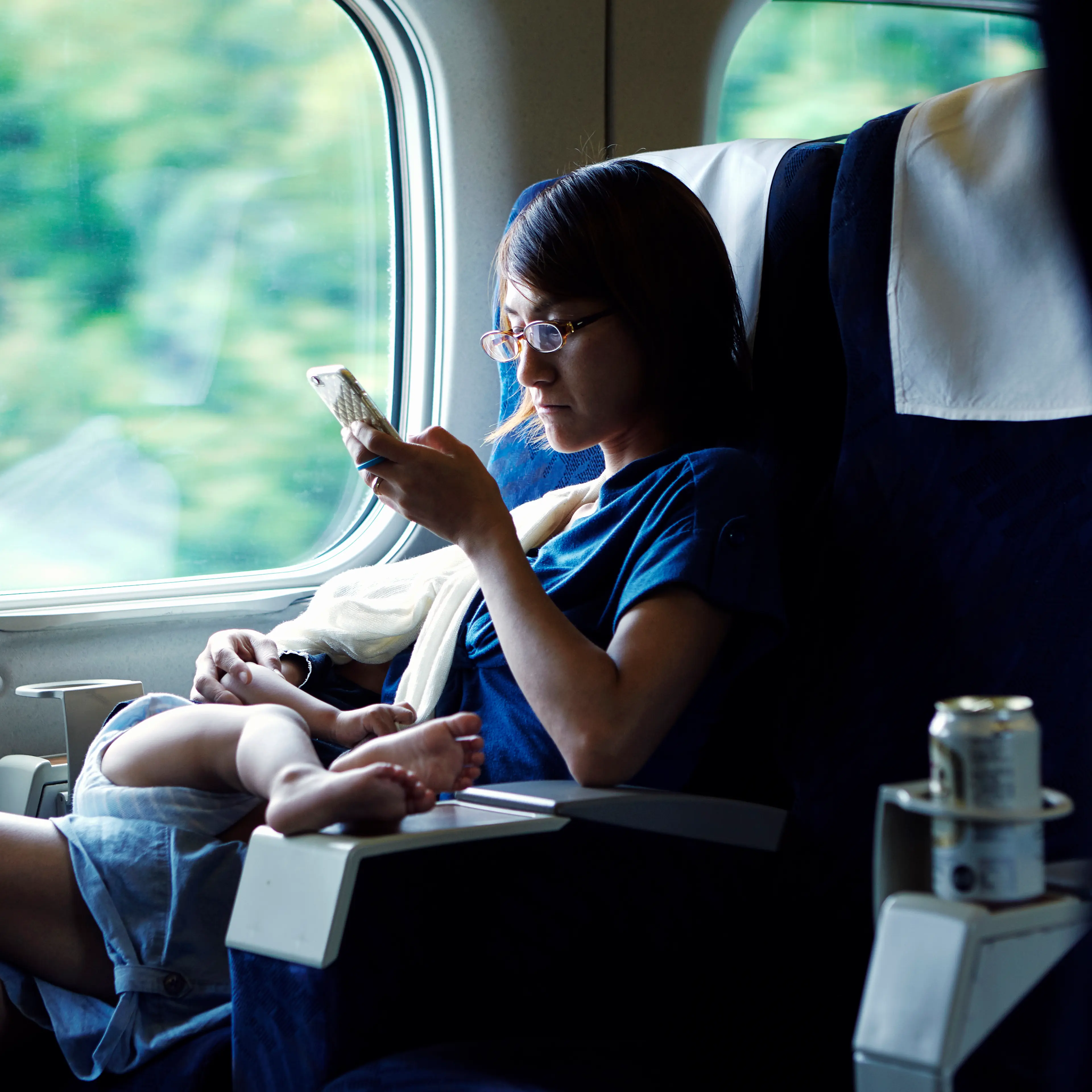 Mother using smartphone while breastfeeding on train