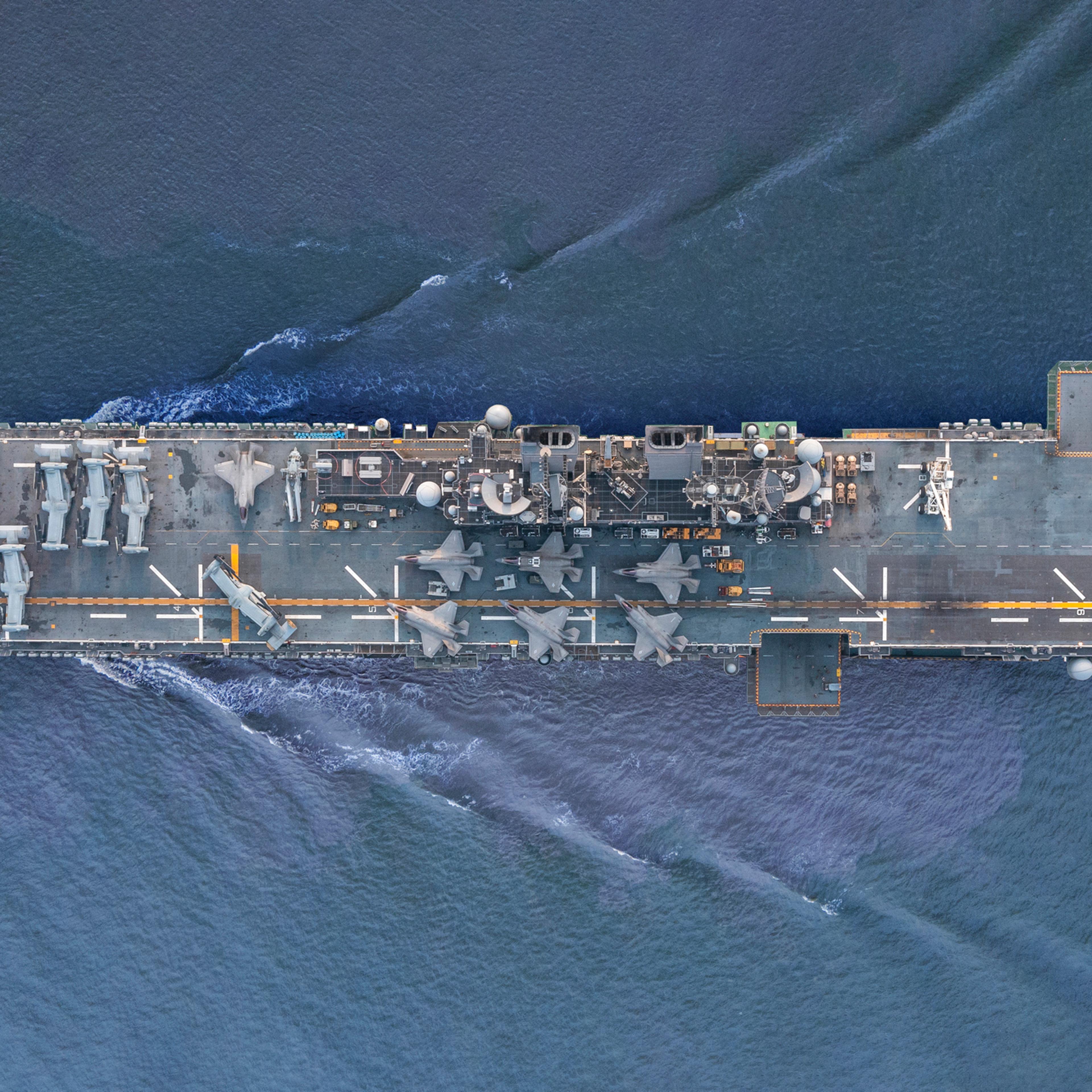 Aerial view/A fighter aircraft carrier sailing in the middle of the sea.