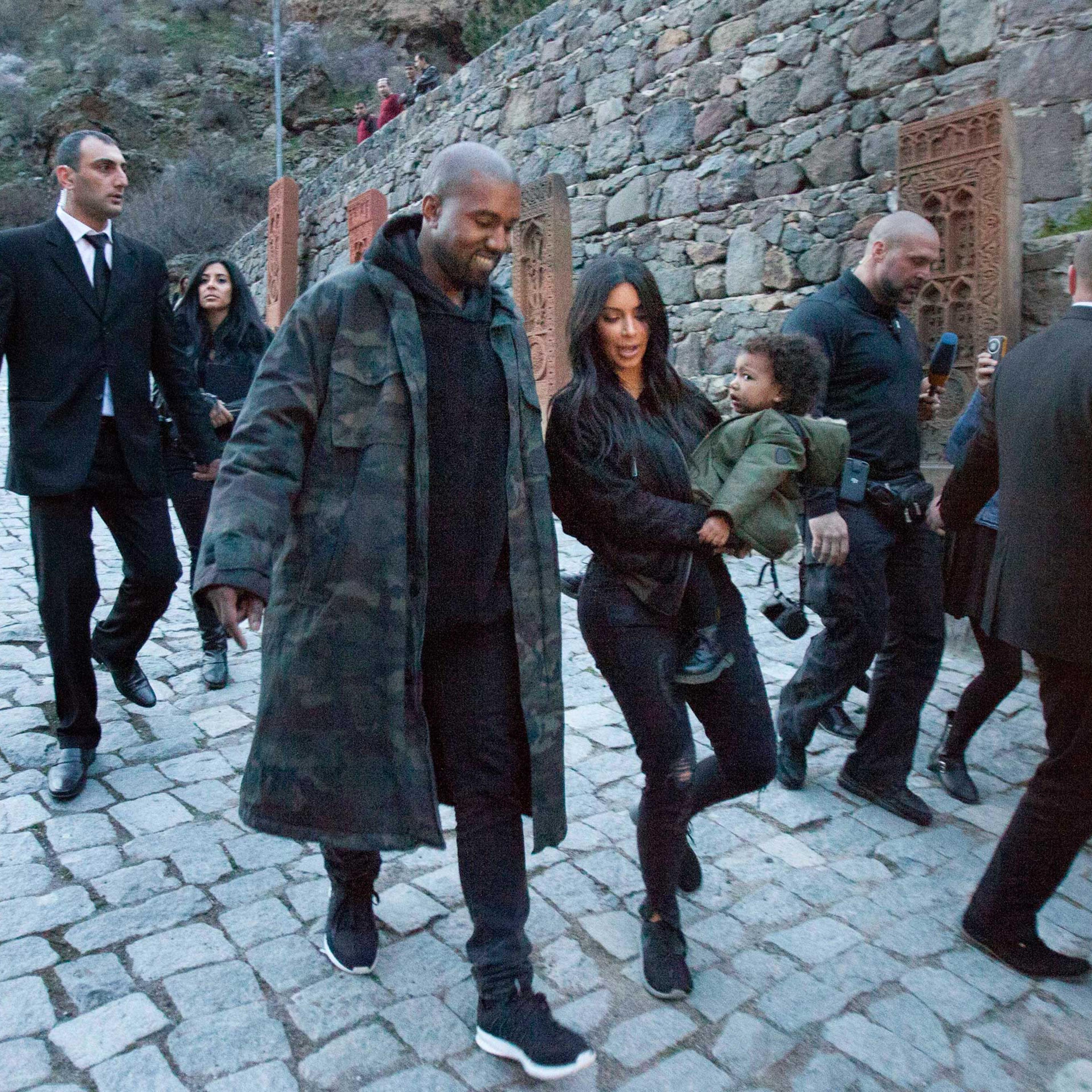 U.S. TV personality Kim Kardashian, center, carriers daughter North as she walks alongside her husband Kanye West visit the Geghard Monastery near Goght, Armenia, April 9, 2015.