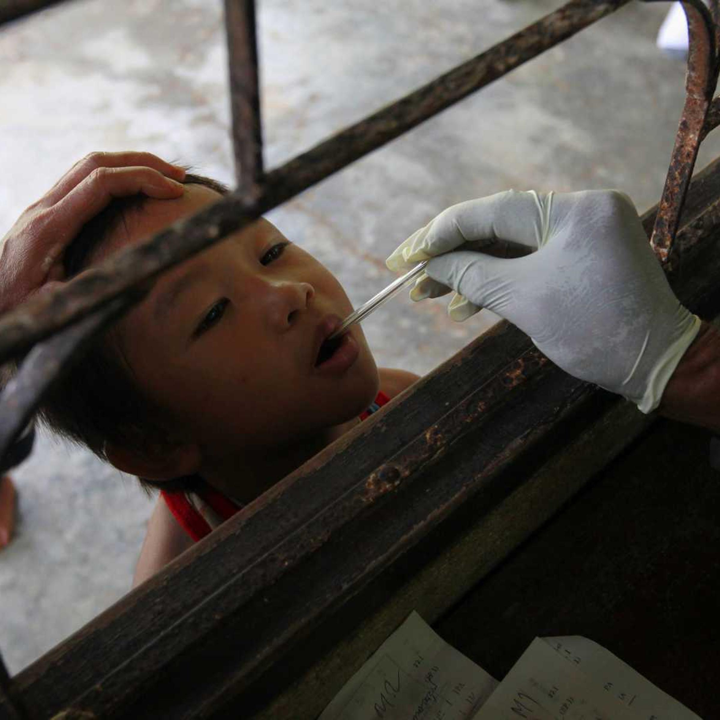 A Thai public-health official places a thermometer into a child's mouth at a malaria clinic in Sai Yoke district, Kanchanaburi province, Thailand, on Oct. 26, 2012