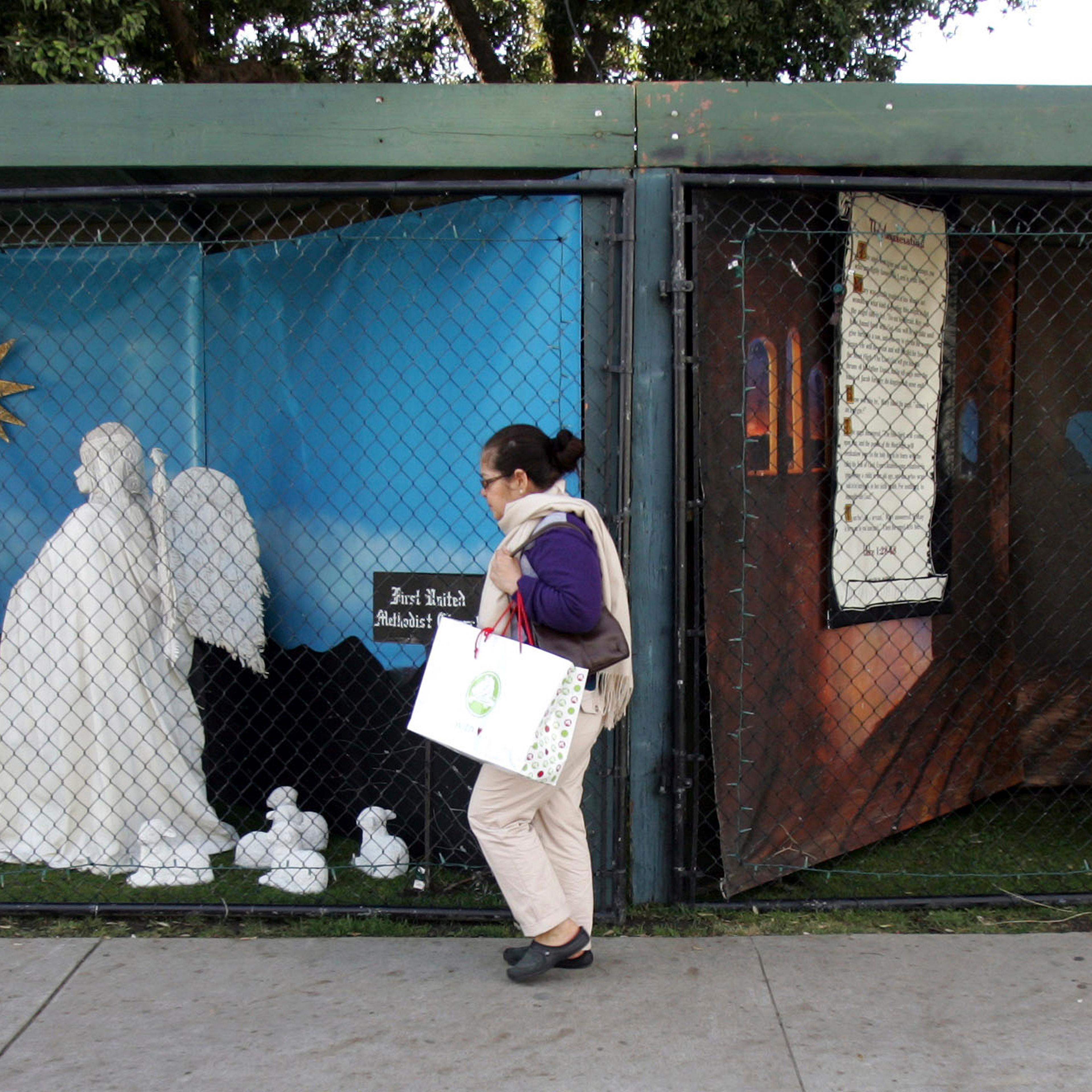 In this Dec. 13, 2011 file photo, a woman walks past a two of the traditional displays showing the Nativity scene along Ocean Avenue at Palisades Park in Santa Monica, Calif.