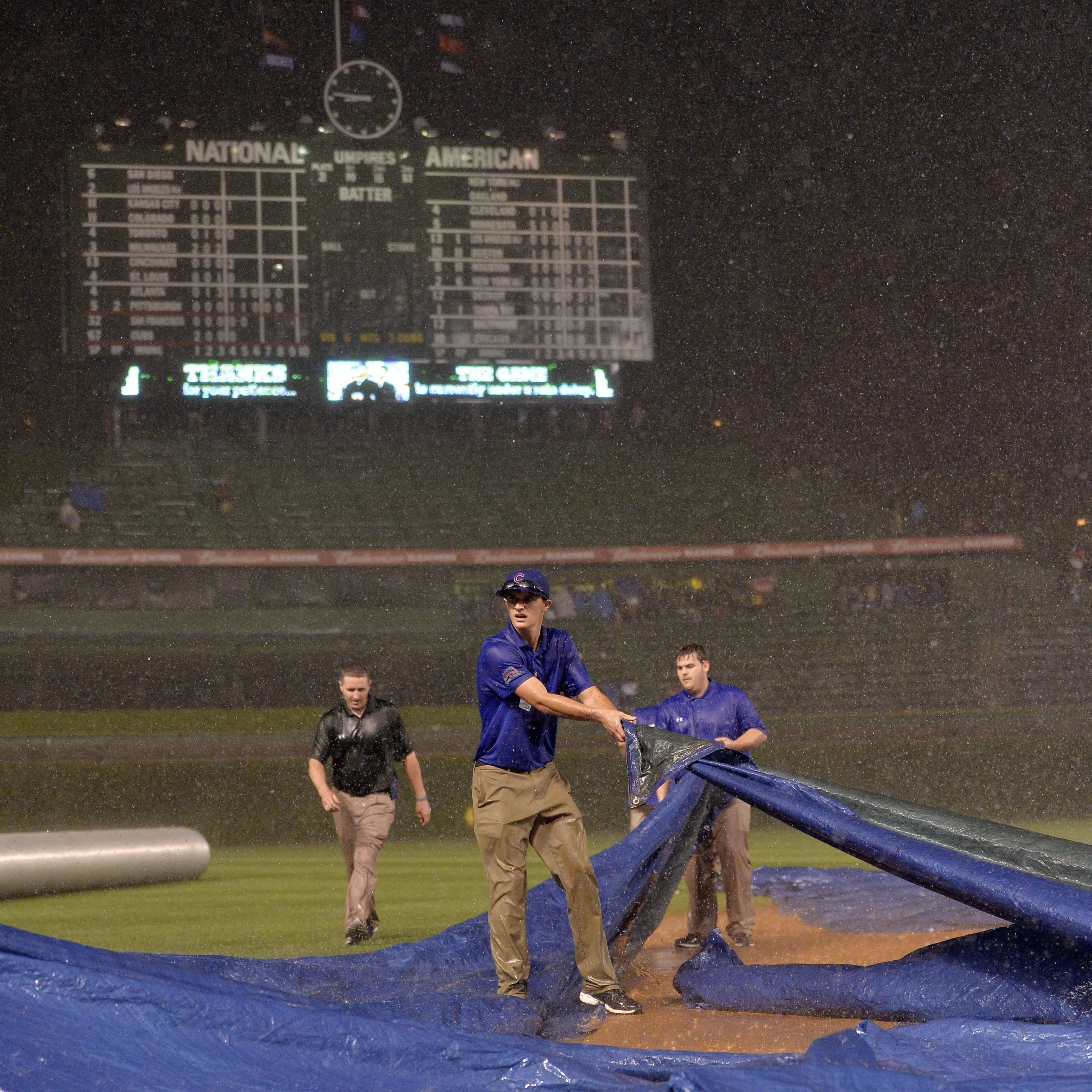 Chicago Cubs ground crew members struggle to get the tarp on the field as rain falls during the fifth inning of the Chicago Cubs game against the San Francisco Giants at Wrigley Field on August 19, 2014 in Chicago.