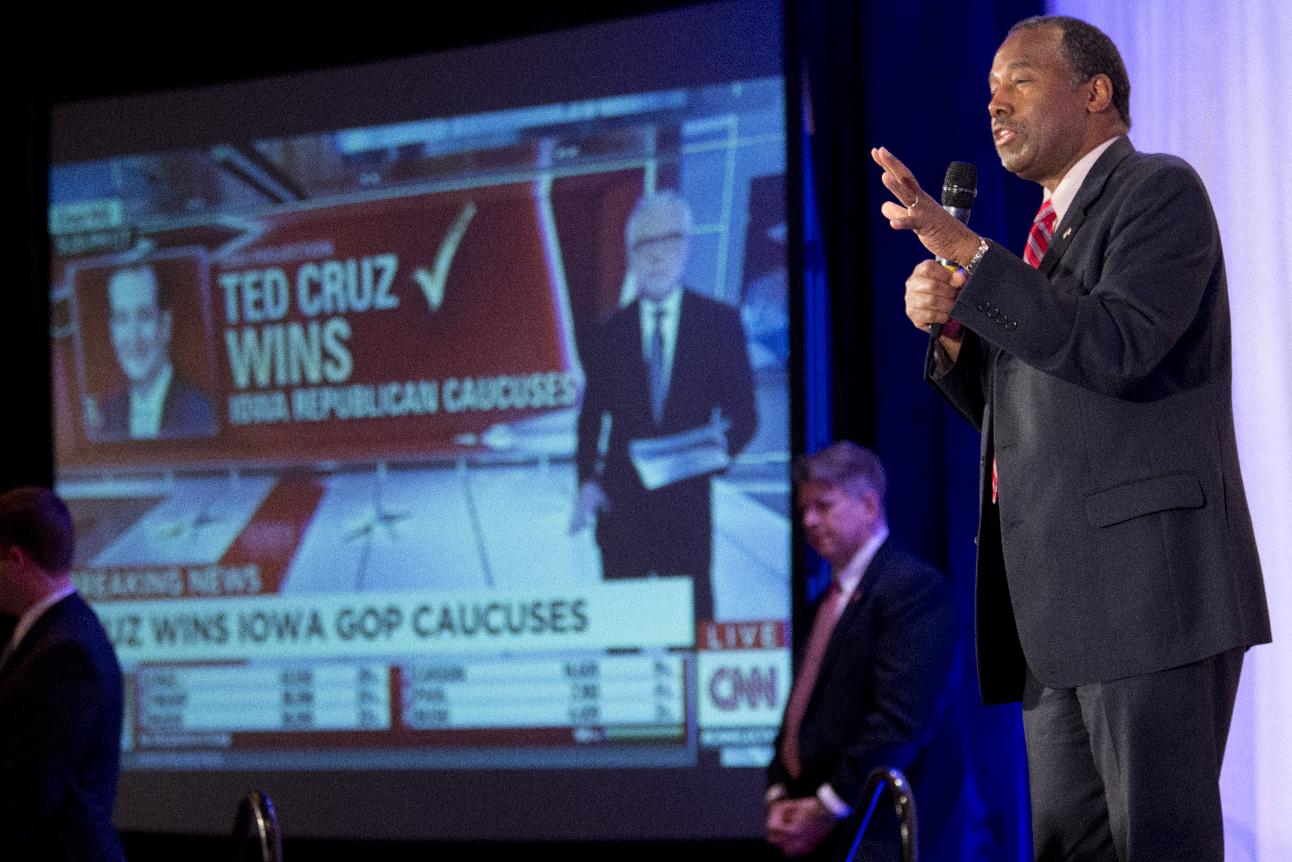 Ben Carson speaks to supporters at his campaign's Caucus Night Rally, Monday, Feb. 1, 2016, in West Des Moines, Iowa as a video screen shows a headline reporting Sen. Ted Cruz, R-Texas, the winner of the Iowa Caucus as Republican presidential candidate.