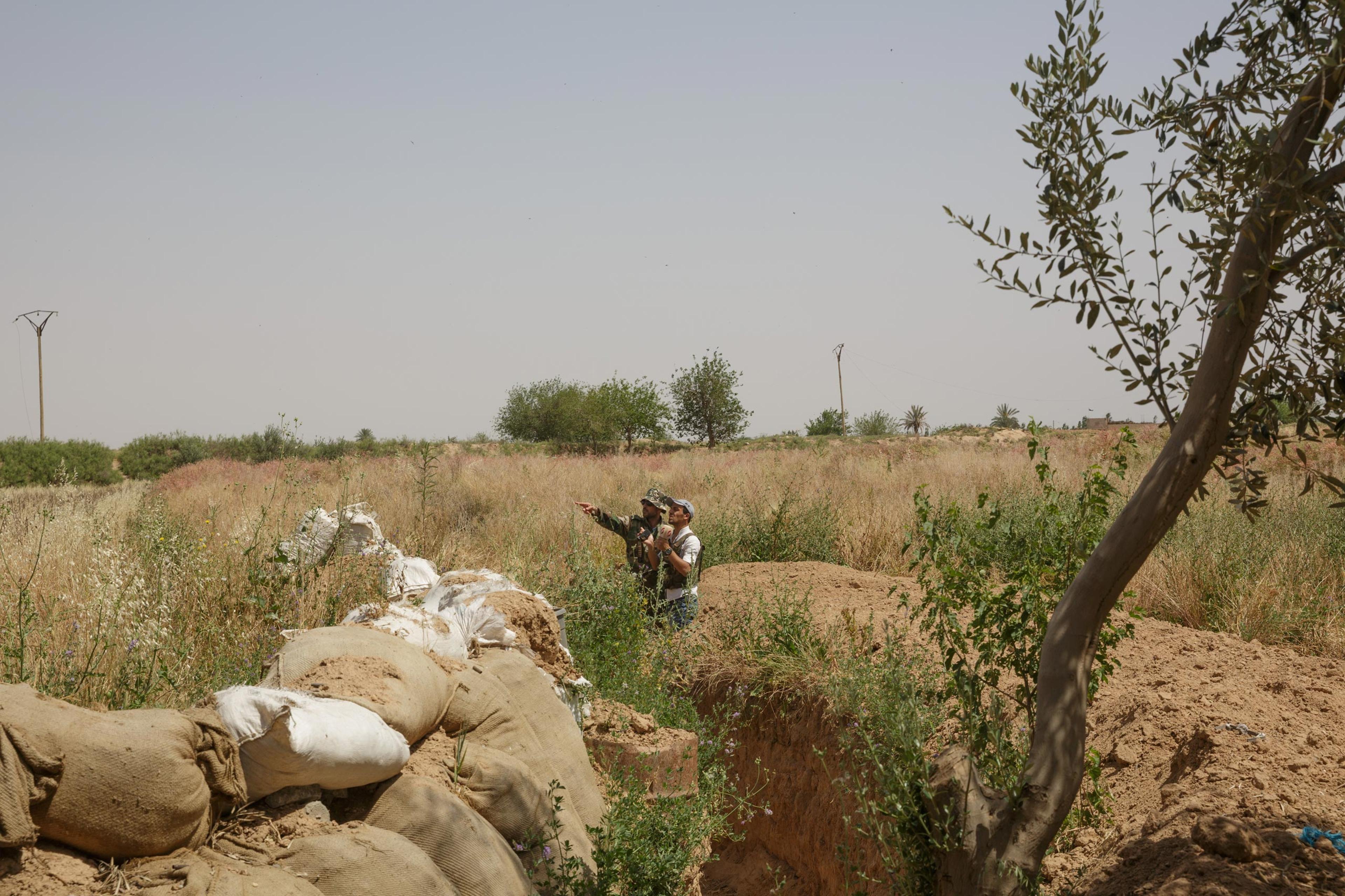A Syrian military officer points out a nearby ISIS position on the outskirts of the besieged city of Deir-ez Zor, May 22, 2015.