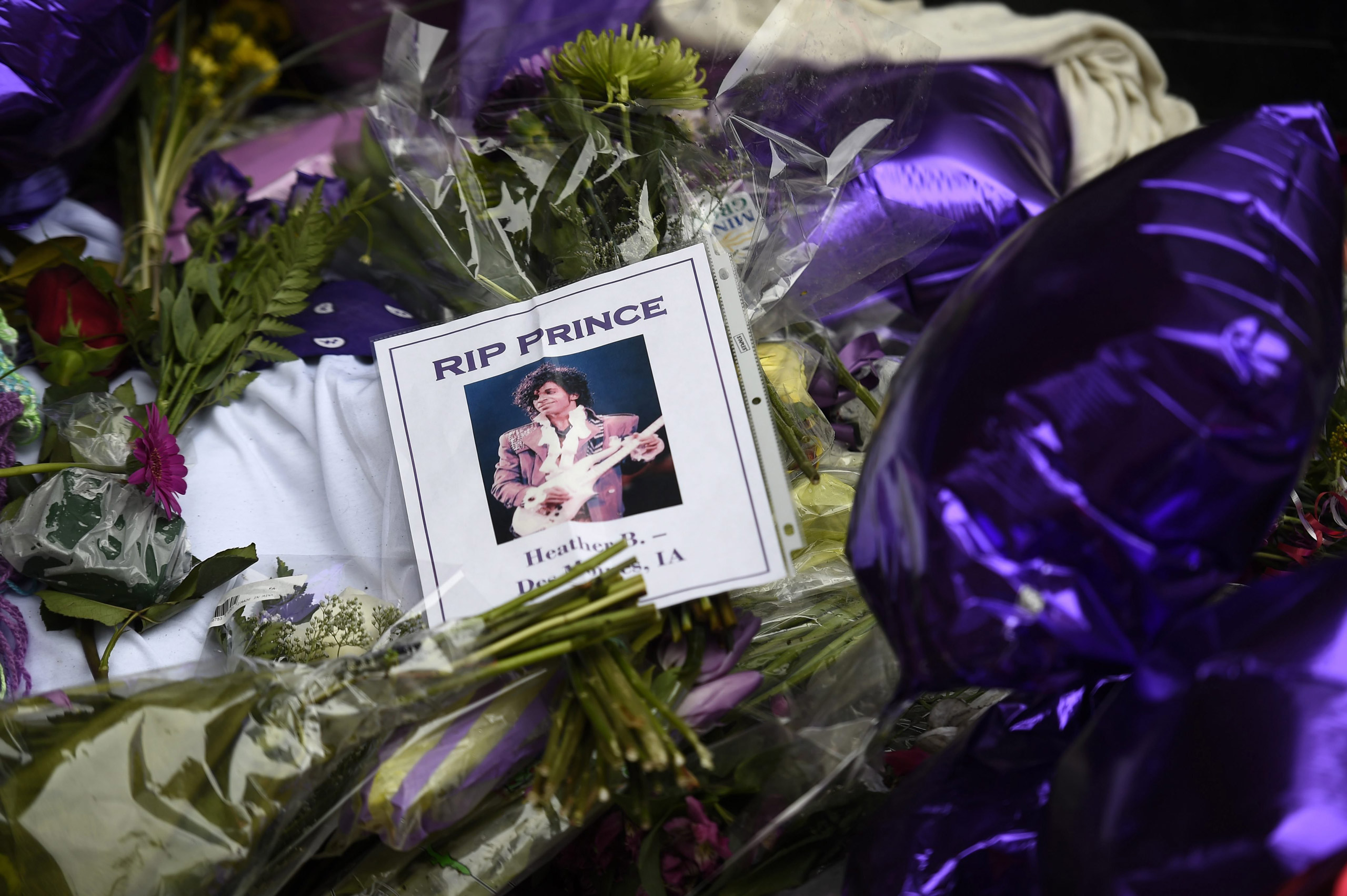epa05272572 Fans leave flowers, photographs and balloons to a makeshift memorial under a star bearing Prince's name on an outside wall of First Avenue, the nightclub where Prince got his start, in Minneapolis, Minnesota, USA, 22 April 2016. US singer-son