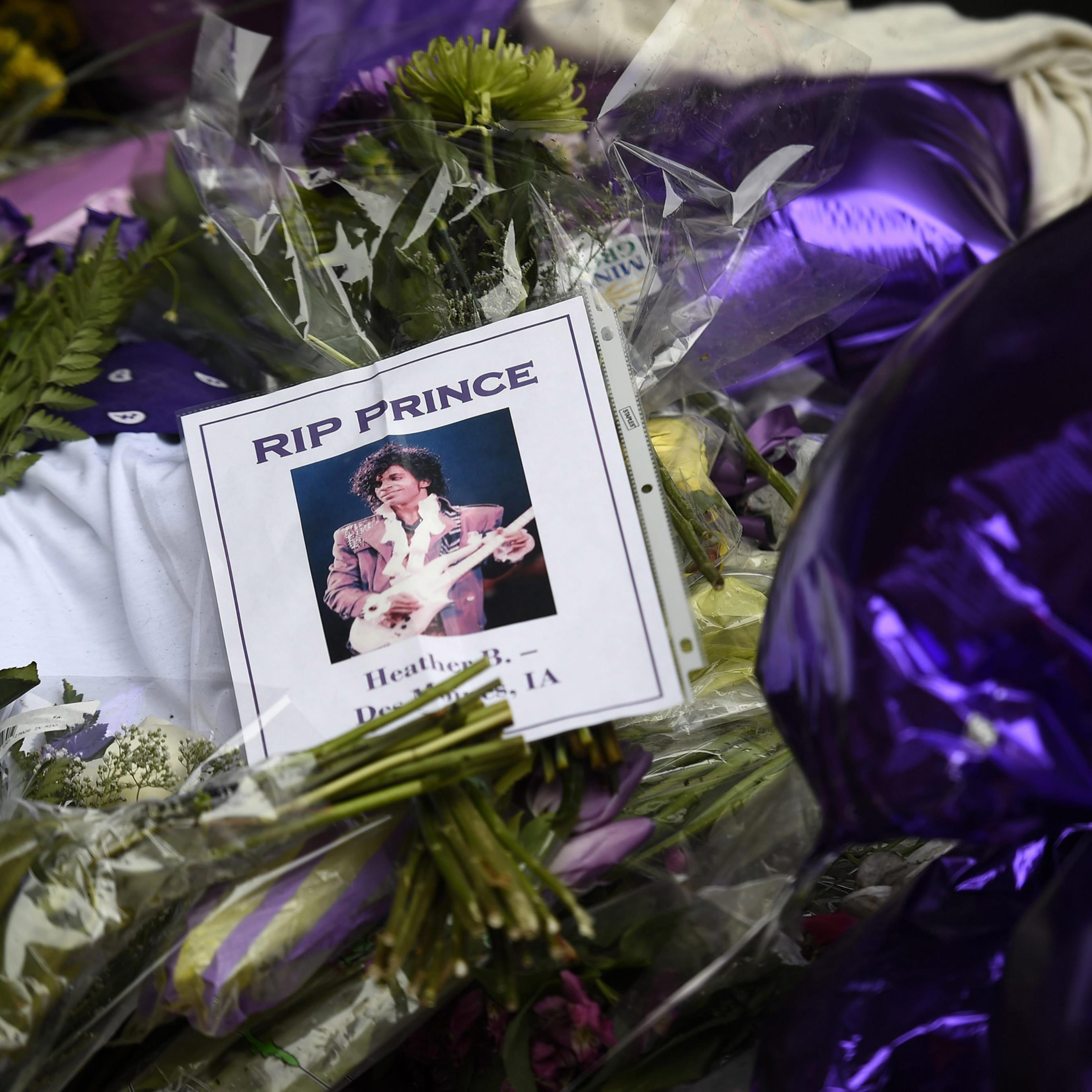 epa05272572 Fans leave flowers, photographs and balloons to a makeshift memorial under a star bearing Prince's name on an outside wall of First Avenue, the nightclub where Prince got his start, in Minneapolis, Minnesota, USA, 22 April 2016. US singer-son