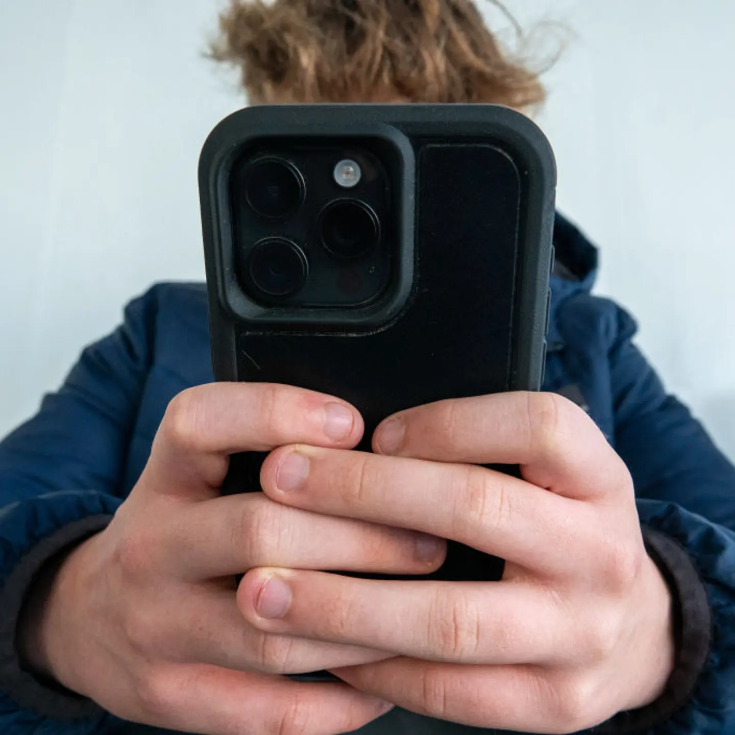 A 14-year-old boy looks at a iPhone screen in Portsmouth, England on Oct. 20, 2024.