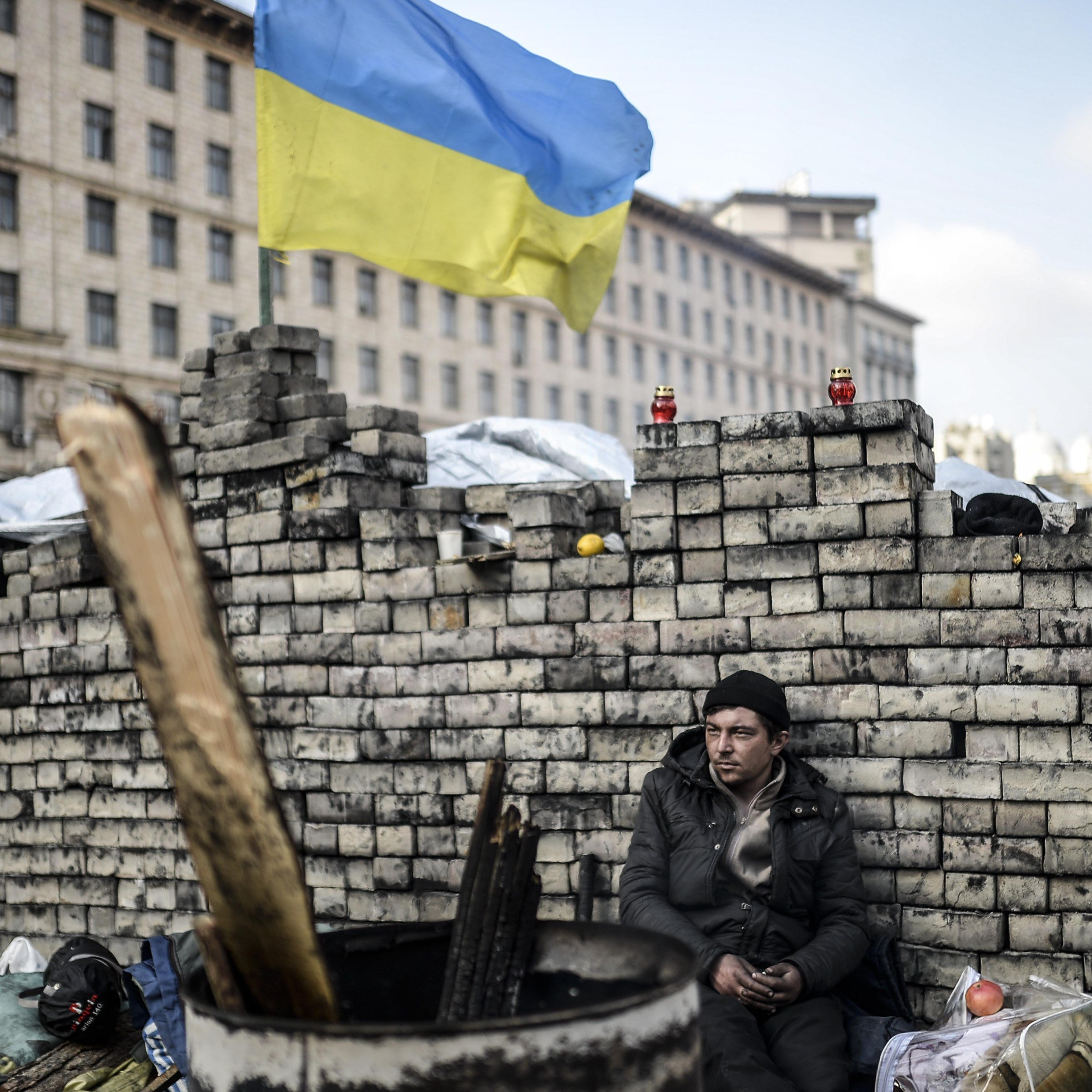 An anti-government protester sits behind a barricade on Kiev's Independence Square on February 24, 2014.