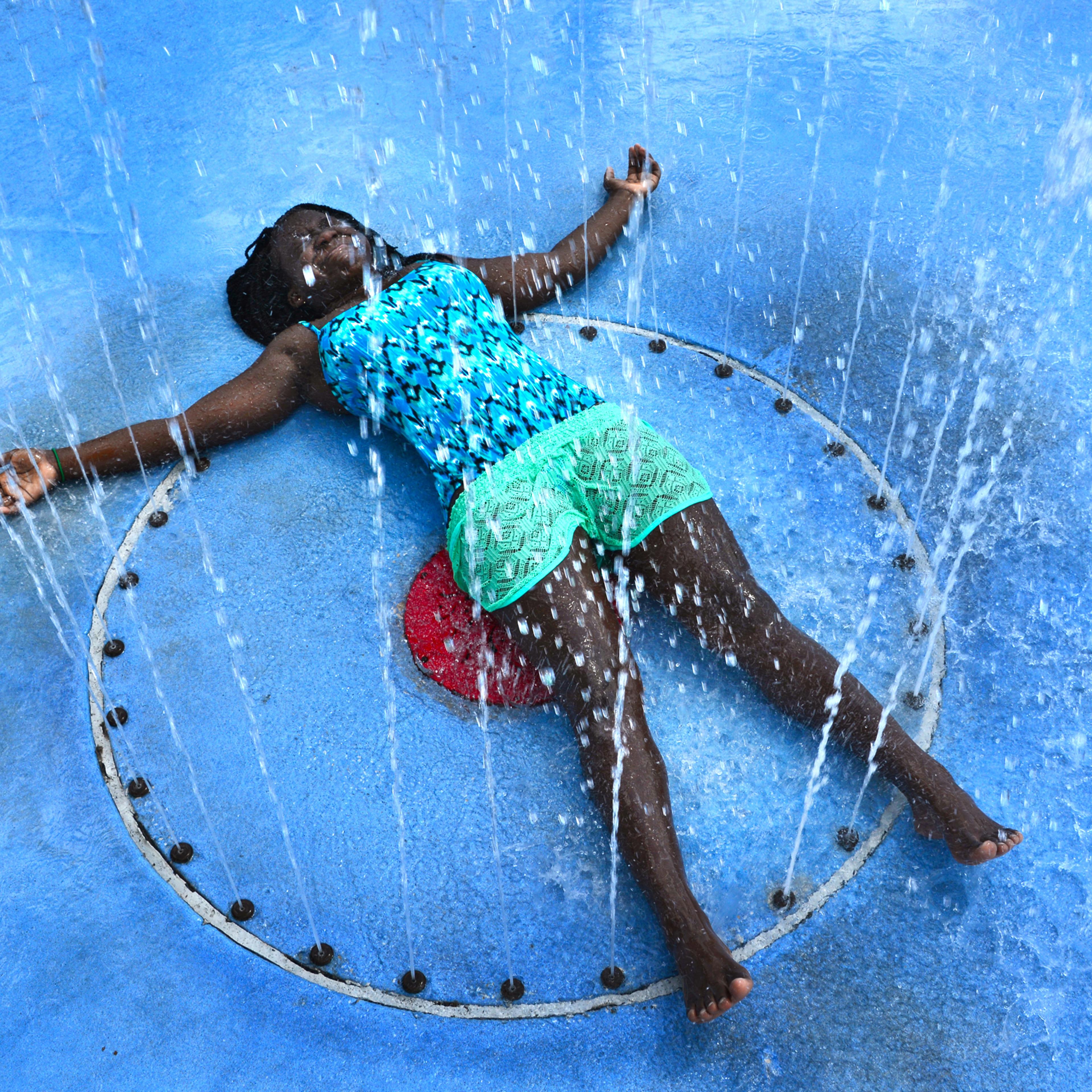 With the temperature in the mid 90's, Carliya Dove, 12, soaks up the full effects of the play fountain in Julius Guinyard Park in Jacksonville, Fla., to beat the afternoon heat on Wednesday July 20, 2016. (Bob Mack/The Florida Times-Union via AP)