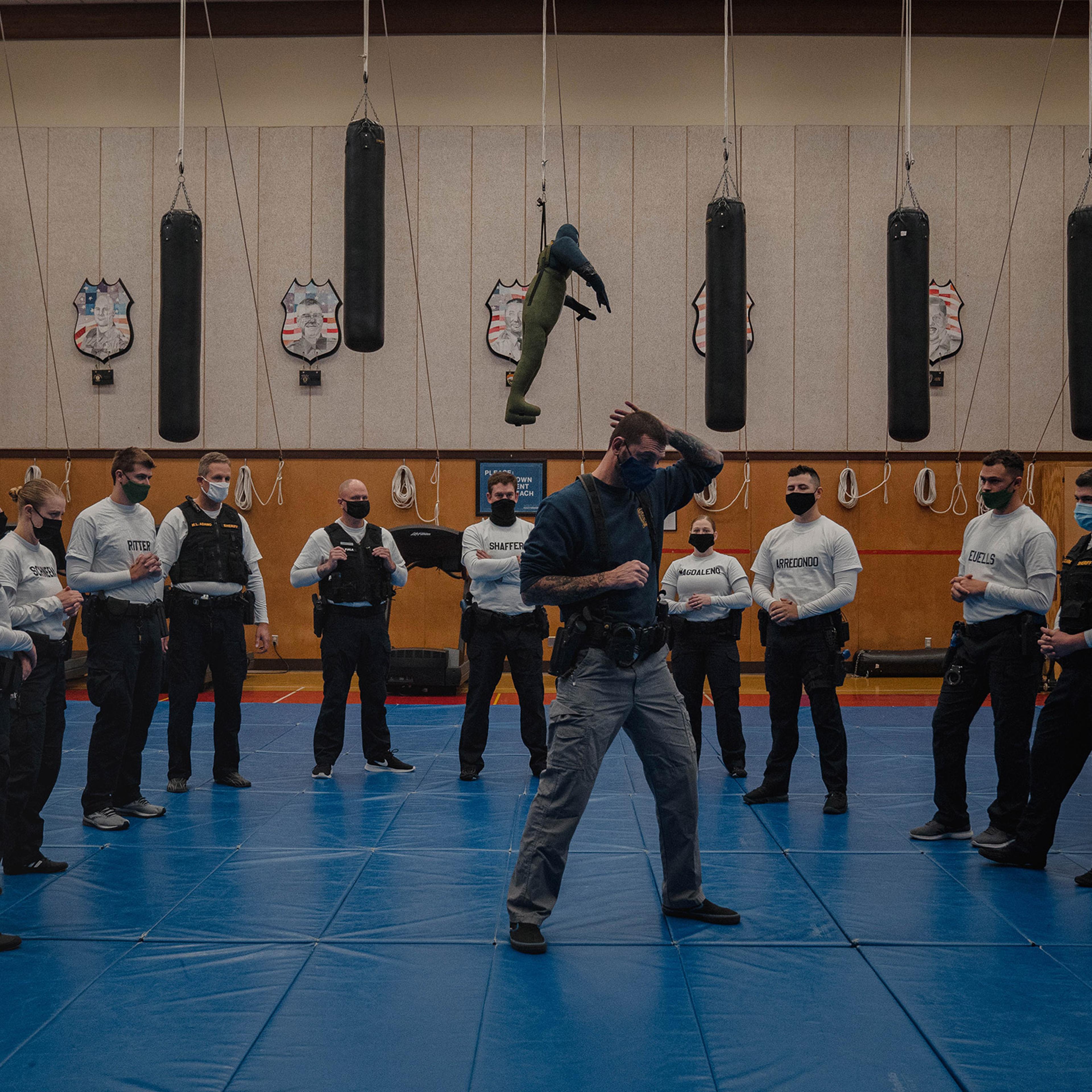 With punching bags and dummies overhead, instructor Javier Sola teaches frisking and handcuffing methods to police recruits at the Washington State Criminal Justice Training Commission facility in Burien, Wash., on Oct. 22. Washington State requires all