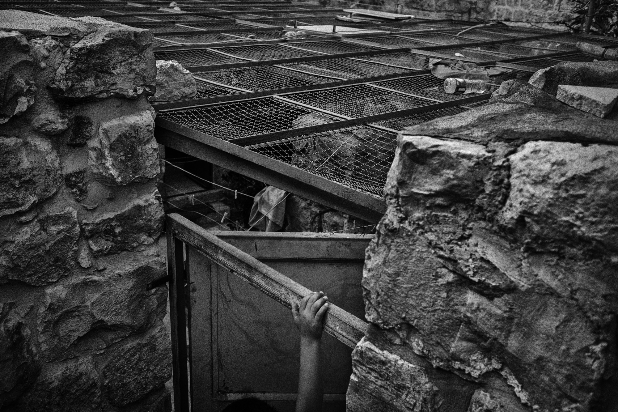 Amer Quneibi plays in the courtyard of his house, where his family has lived for generations. The metal cover was installed to protect the family from stones and garbage that is regularly dumped by Jewish settlers who live nearby. Hebron, November 2015.