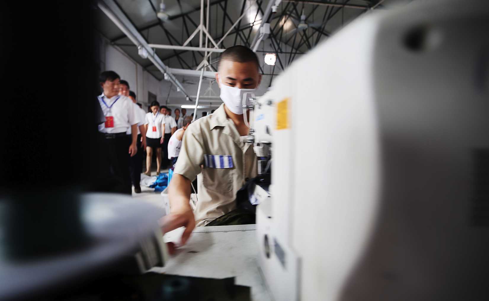 Chinese visitors watch inmates sewing clothes at a prison in Neihuang county, Anyang city, central Chinas Henan province, 25 June 2013.