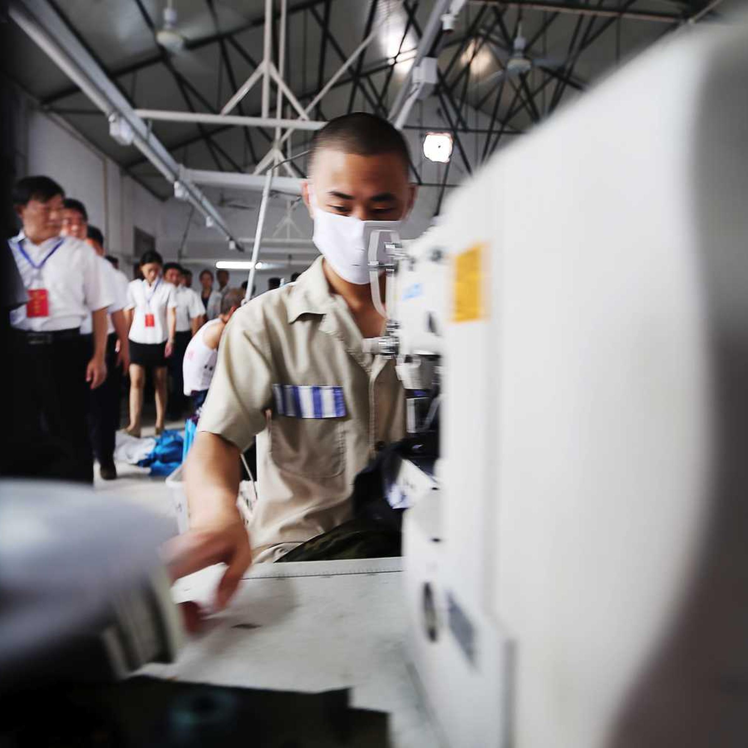 Chinese visitors watch inmates sewing clothes at a prison in Neihuang county, Anyang city, central Chinas Henan province, 25 June 2013.
