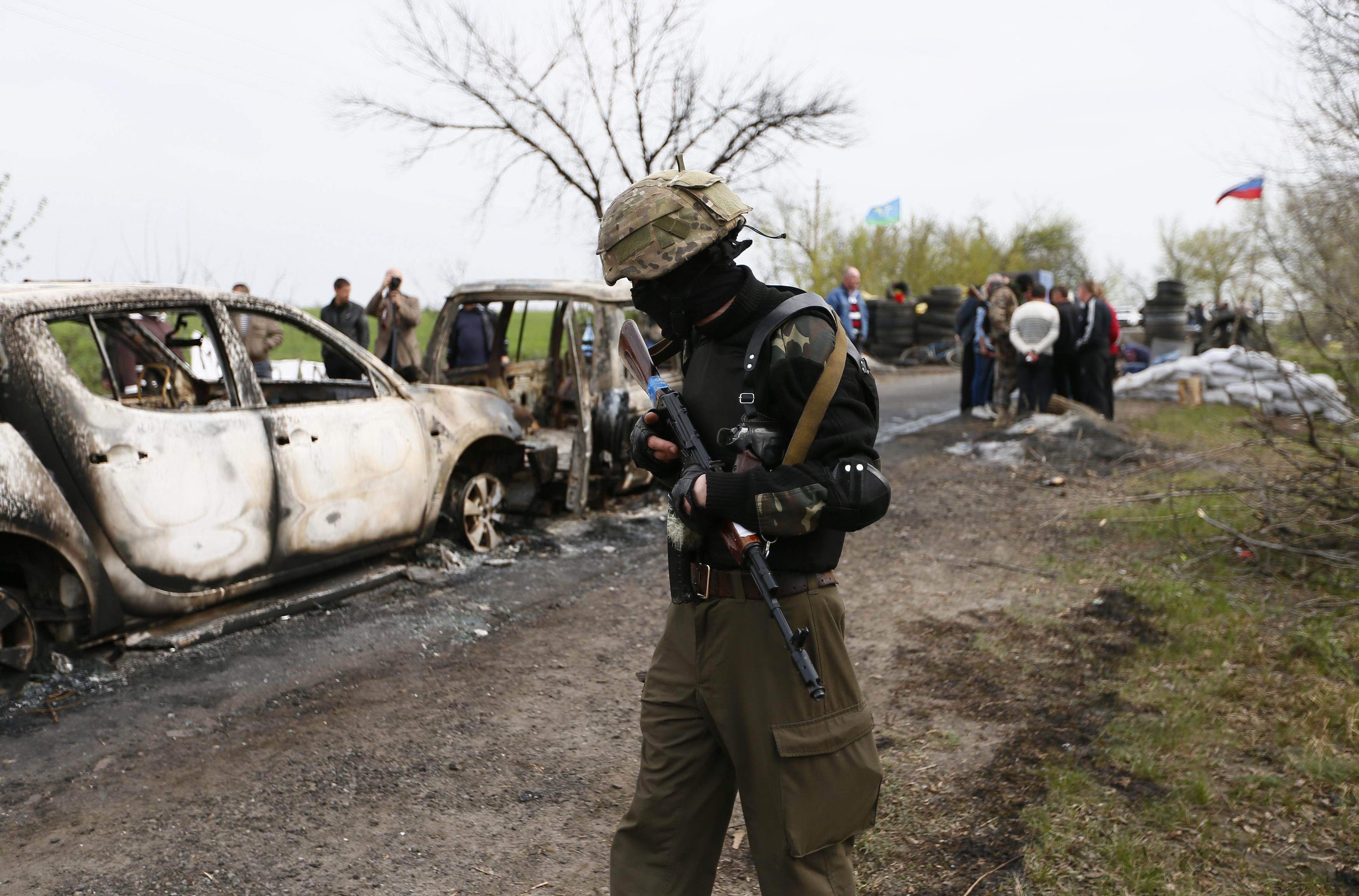A Pro-Russian militant walks near a checkpoint that was the scene of a gunfight overnight near the city of Slaviansk, April 20, 2014.
